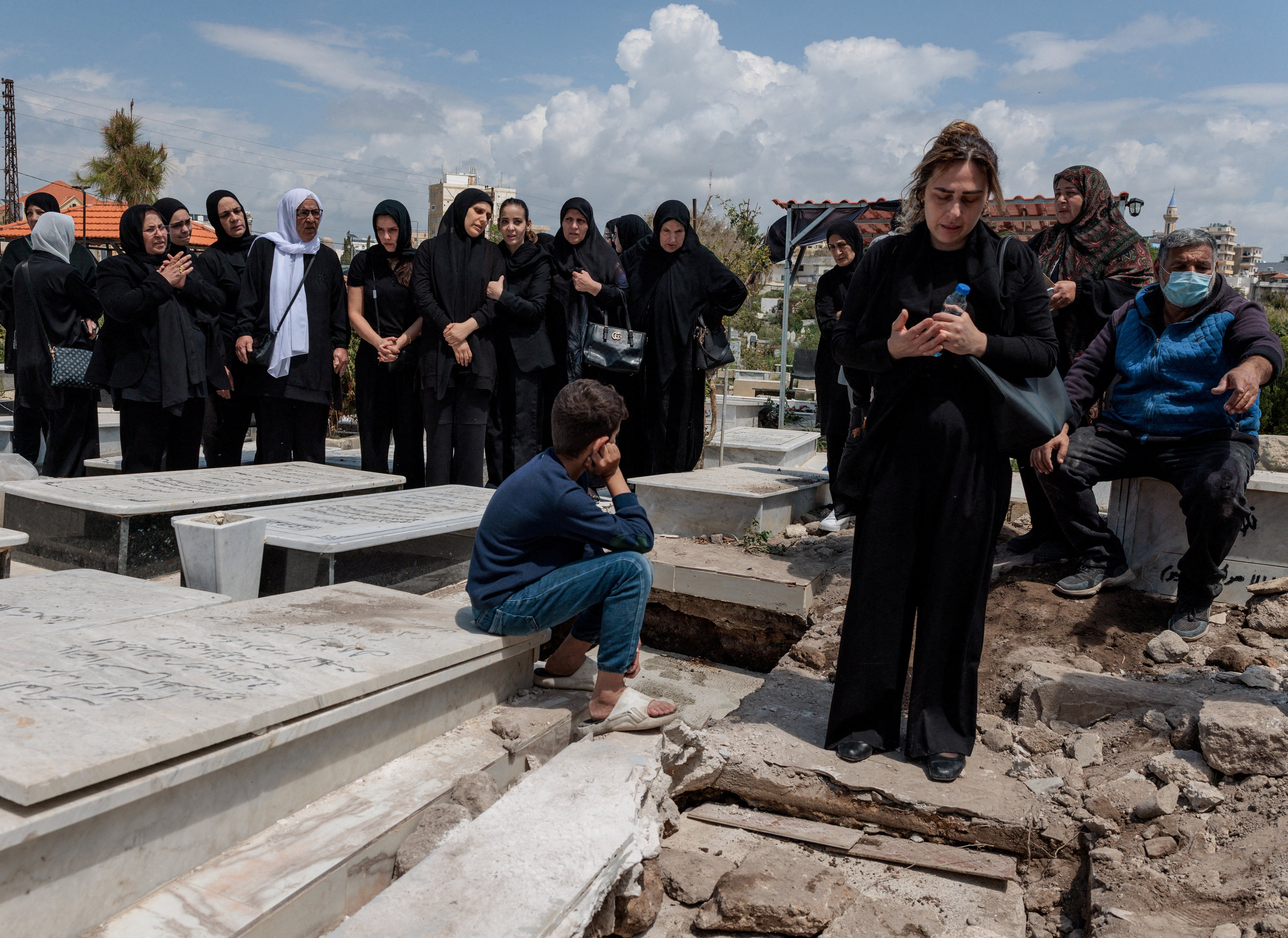 Relatives pray by the graves of Hussein Dbouk, 80, and his Son Rabih Dbouk, 32, victims retrieved from the rubble of a building hit by an Israeli strike just before the ceasefire, following a funeral ceremony, amid a 10-day ceasefire between Lebanon and Israel, in Tyre, southern Lebanon, April 20, 2026.