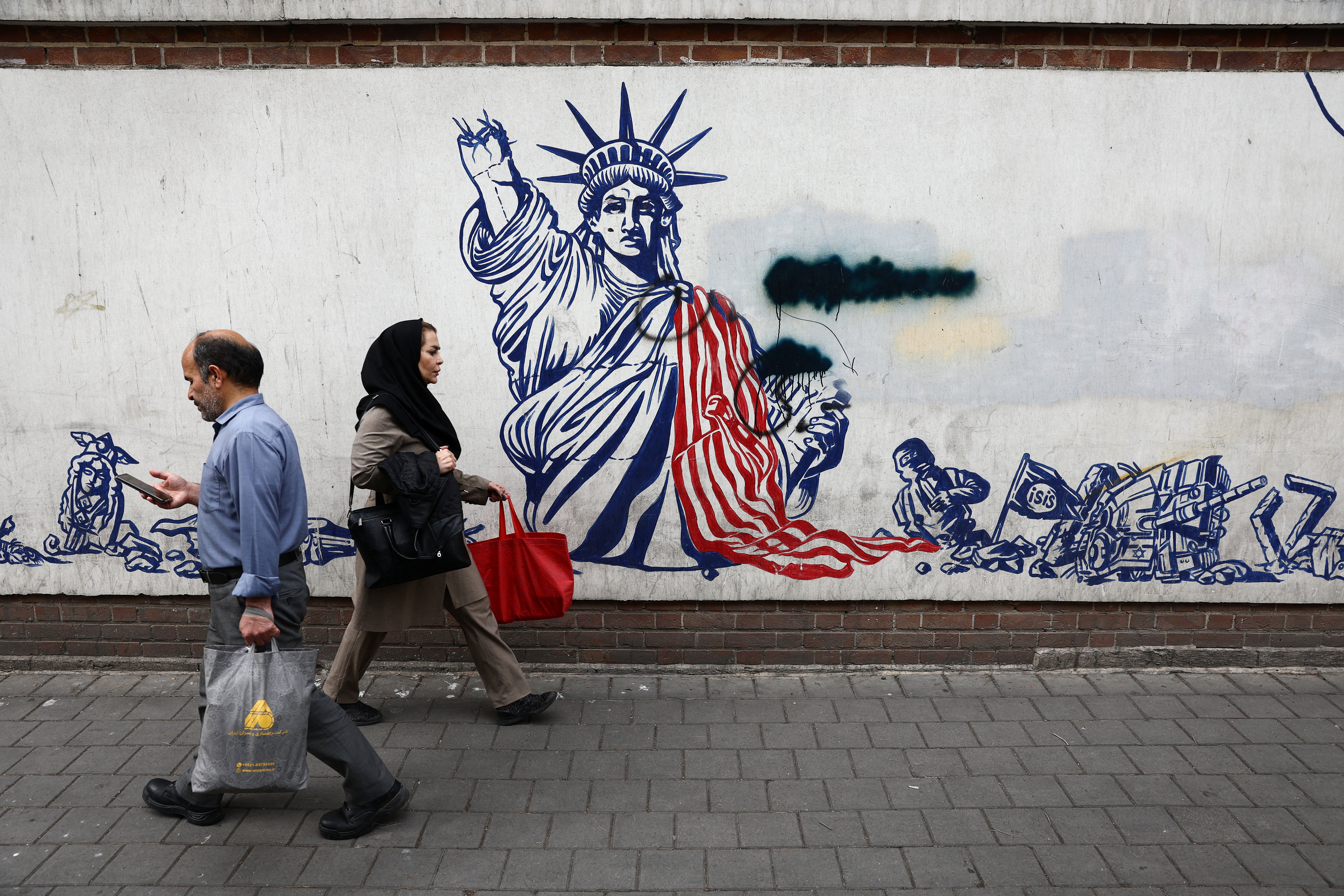 People walk past an anti-U.S. mural on a street, amid a ceasefire between U.S. and Iran, in Tehran, Iran, April 20, 2026. Majid Asgaripour/WANA (West Asia News Agency) via REUTERS ATTENTION EDITORS - THIS PICTURE WAS PROVIDED BY A THIRD PARTY