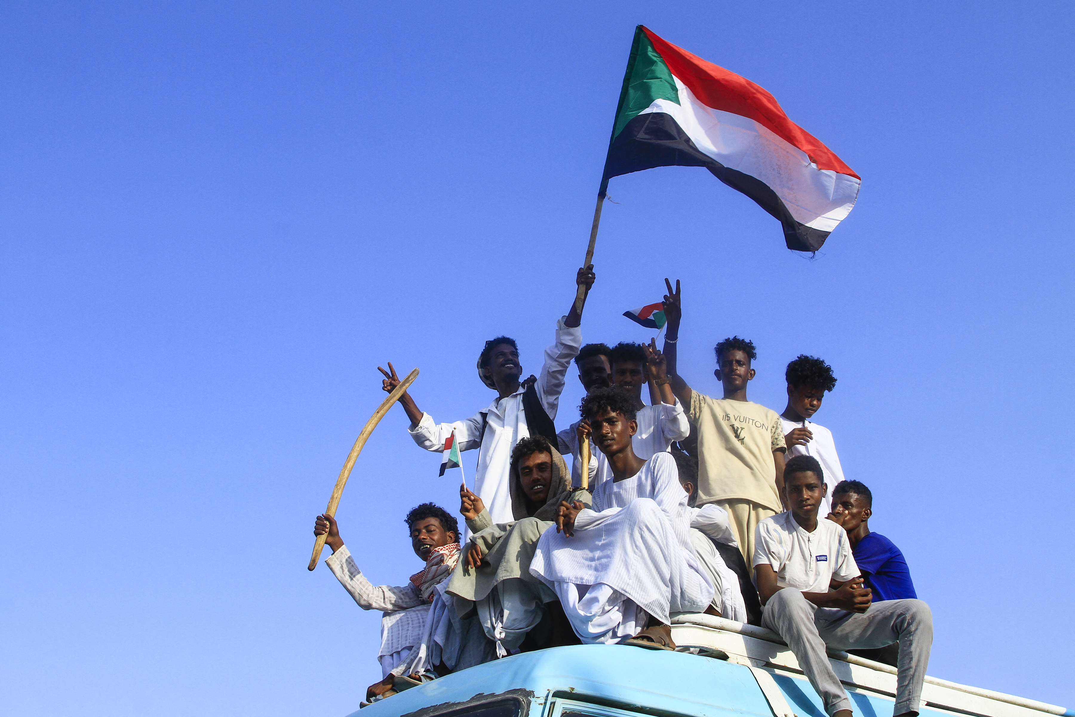 People lift national flags during a rally called for by Sudan's Popular Front for Liberation and Justice in Port Sudan on April 24, 2025, to denounce the siege imposed by the paramilitary Rapid Support Forces (RSF) on El-Fasher city and express support for its residents. Since April 2023, the war between the army and the RSF has killed tens of thousands, uprooted 13 million and created what the UN describes as the world's worst humanitarian crisis. [Photo by AFP]