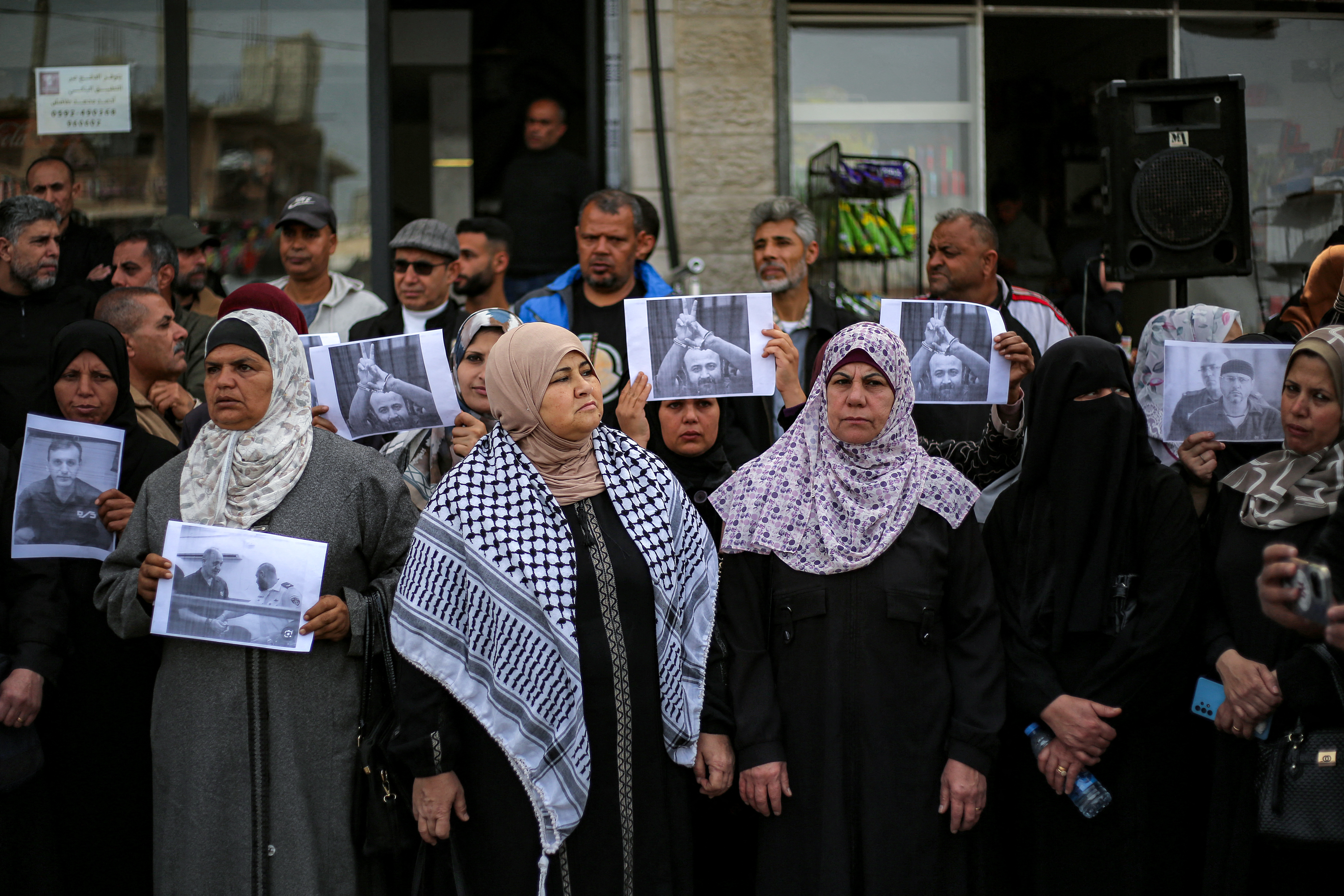 People hold up printed pictures of Marwan Barghouti during a protest.