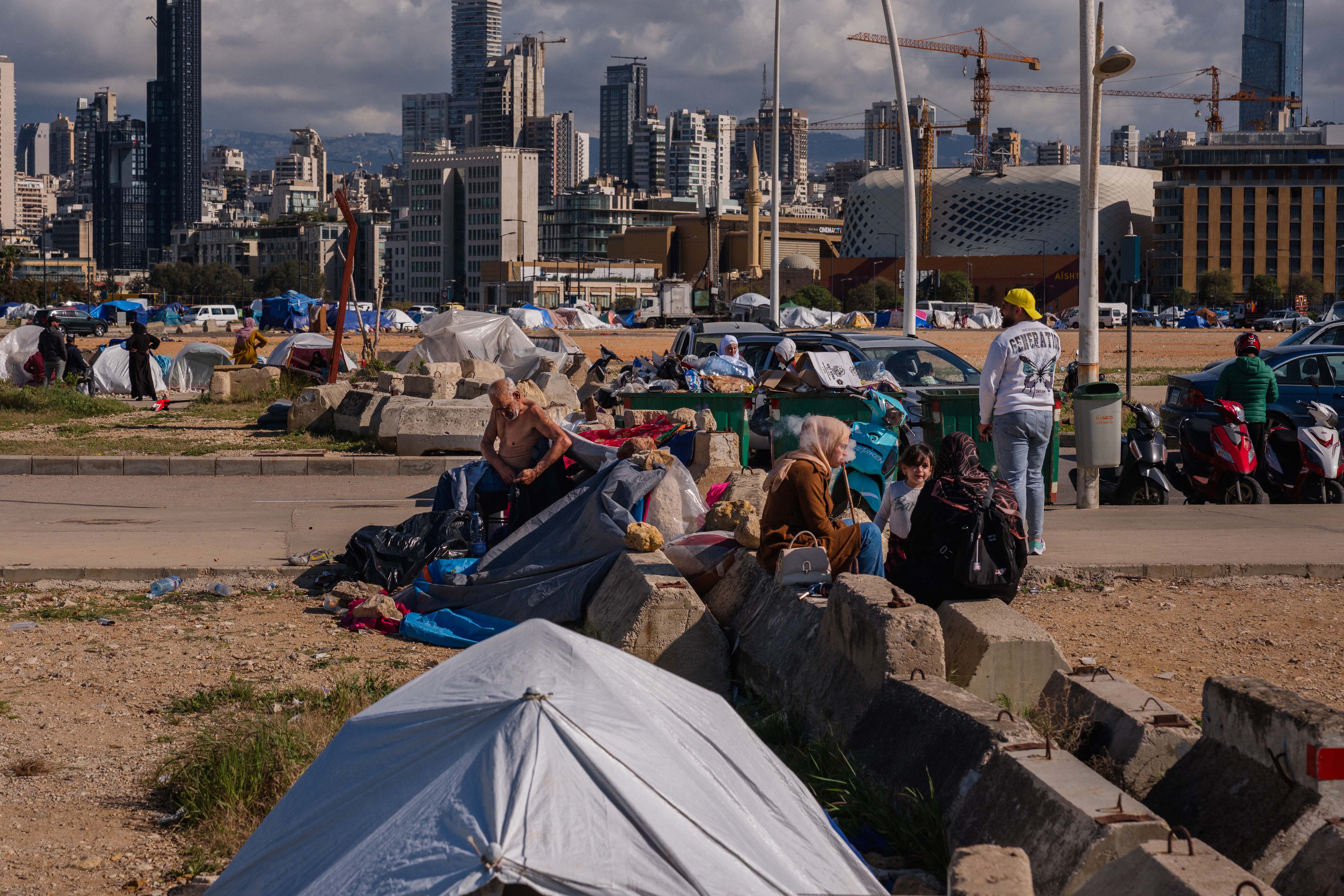 Displaced people sit outside their tents at an unofficial camp erected along Beirut's seafront area on April 6, 2026. [Dimitar Dilkoff/AFP]