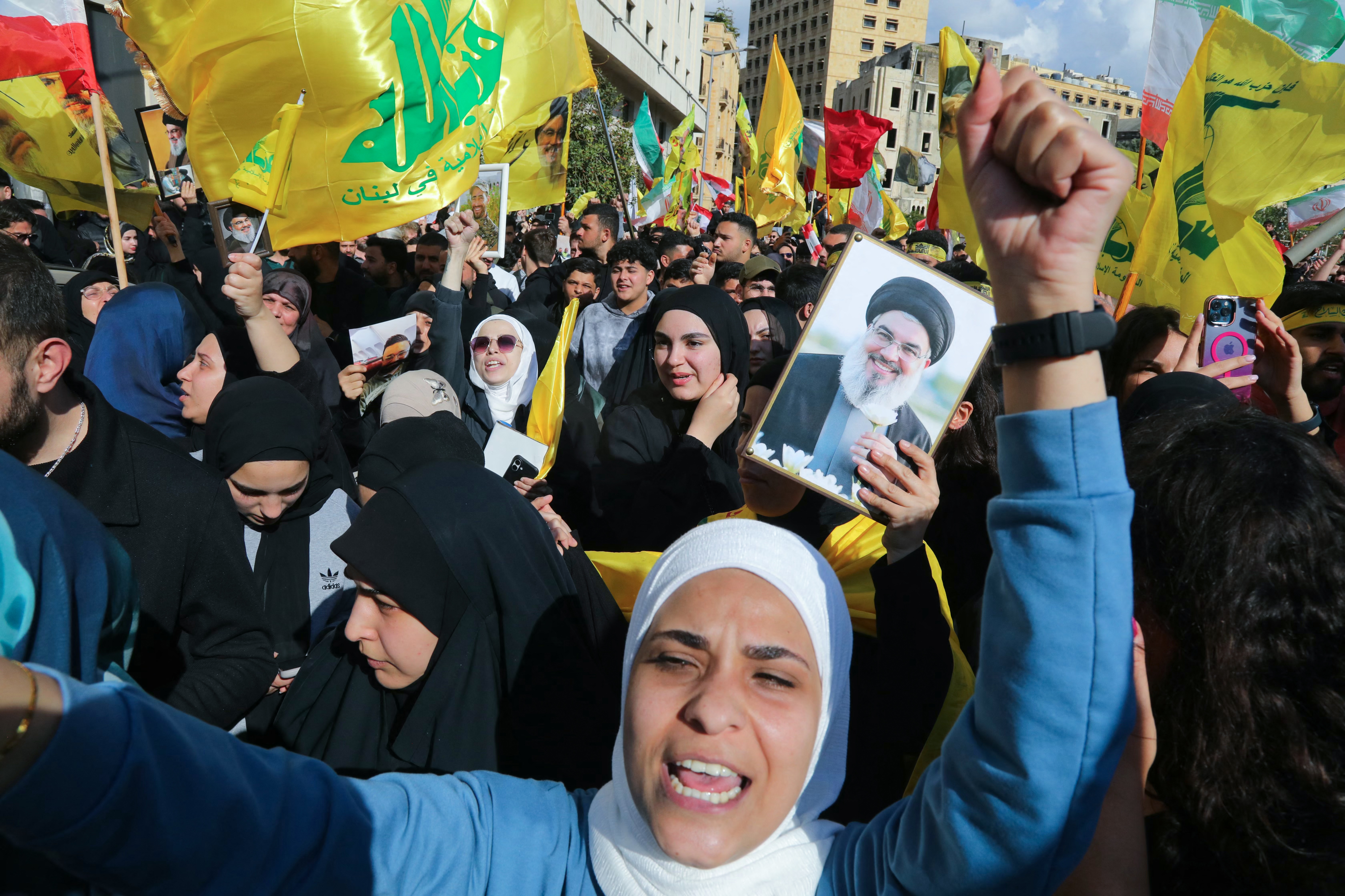Hezbollah supporters, some waving the party flag and holding up an image of Lebanon's slain Hezbollah leader Hassan Nasrallah, demonstrate.