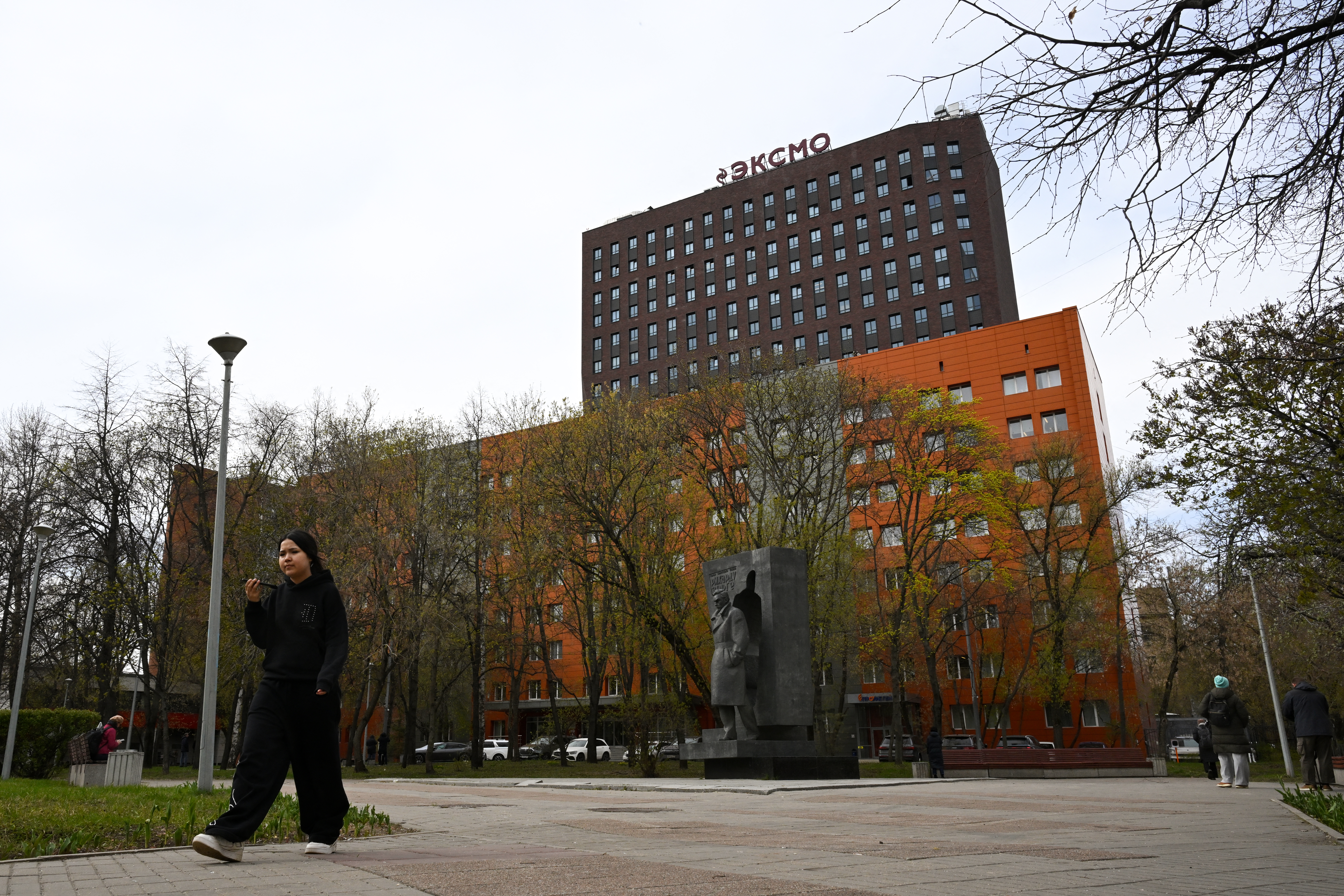 A woman, speaking on the phone, walks past Eksmo's central office building in Moscow