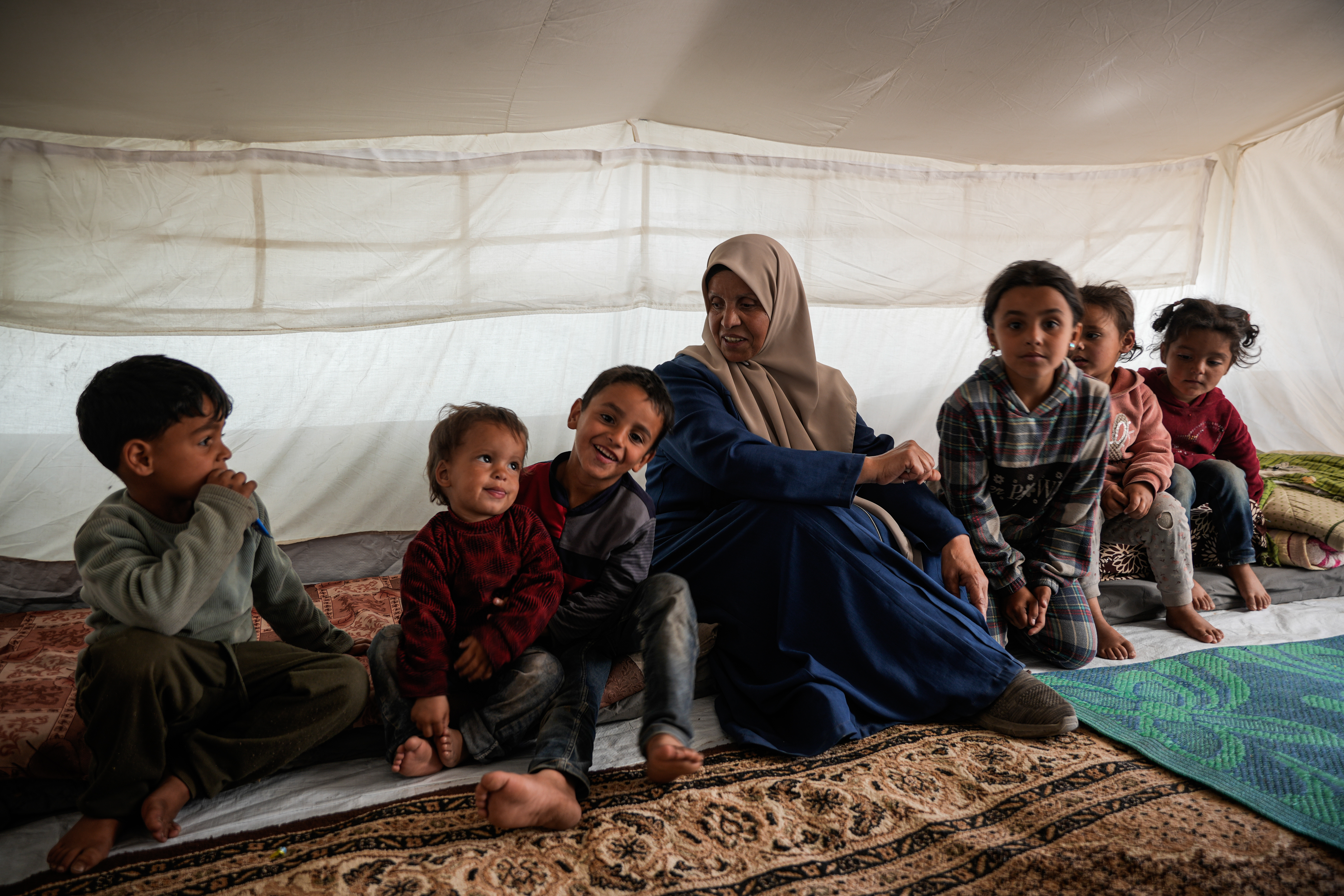 Inaam sits with her six grandchildren, the children of one of her sons who has been held in Israeli prisons for two years [Omar Ashtawy/ Al Jazeera]