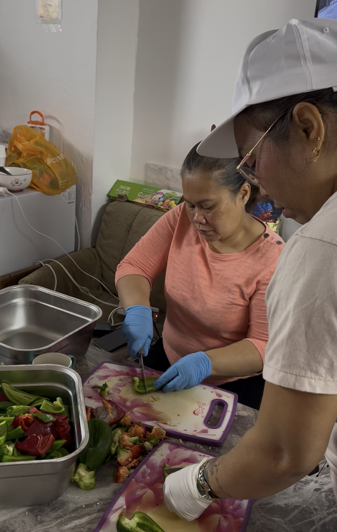 Aragon's team cuts peppers as she cooks chicken in the kitchen. [Justin Salhani/Al Jazeera]