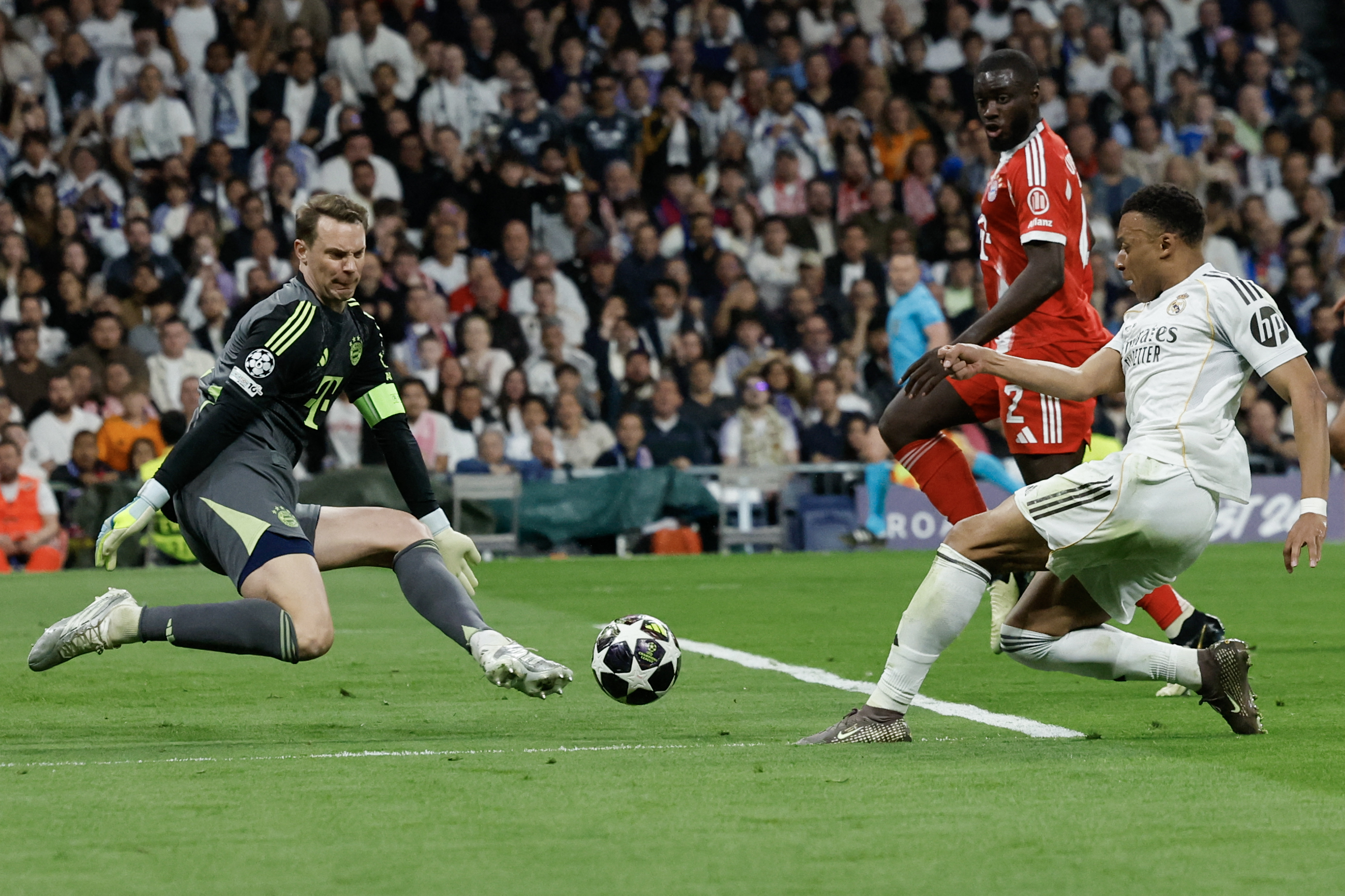 TOPSHOT - Real Madrid's French forward #10 Kylian Mbappe (R) shoots but fails to score past Bayern Munich's German goalkeeper #01 Manuel Neuer during the UEFA Champions League quarter final first leg football match between Real Madrid CF and FC Bayern Munich at Santiago Bernabeu Stadium in Madrid on April 7, 2026.