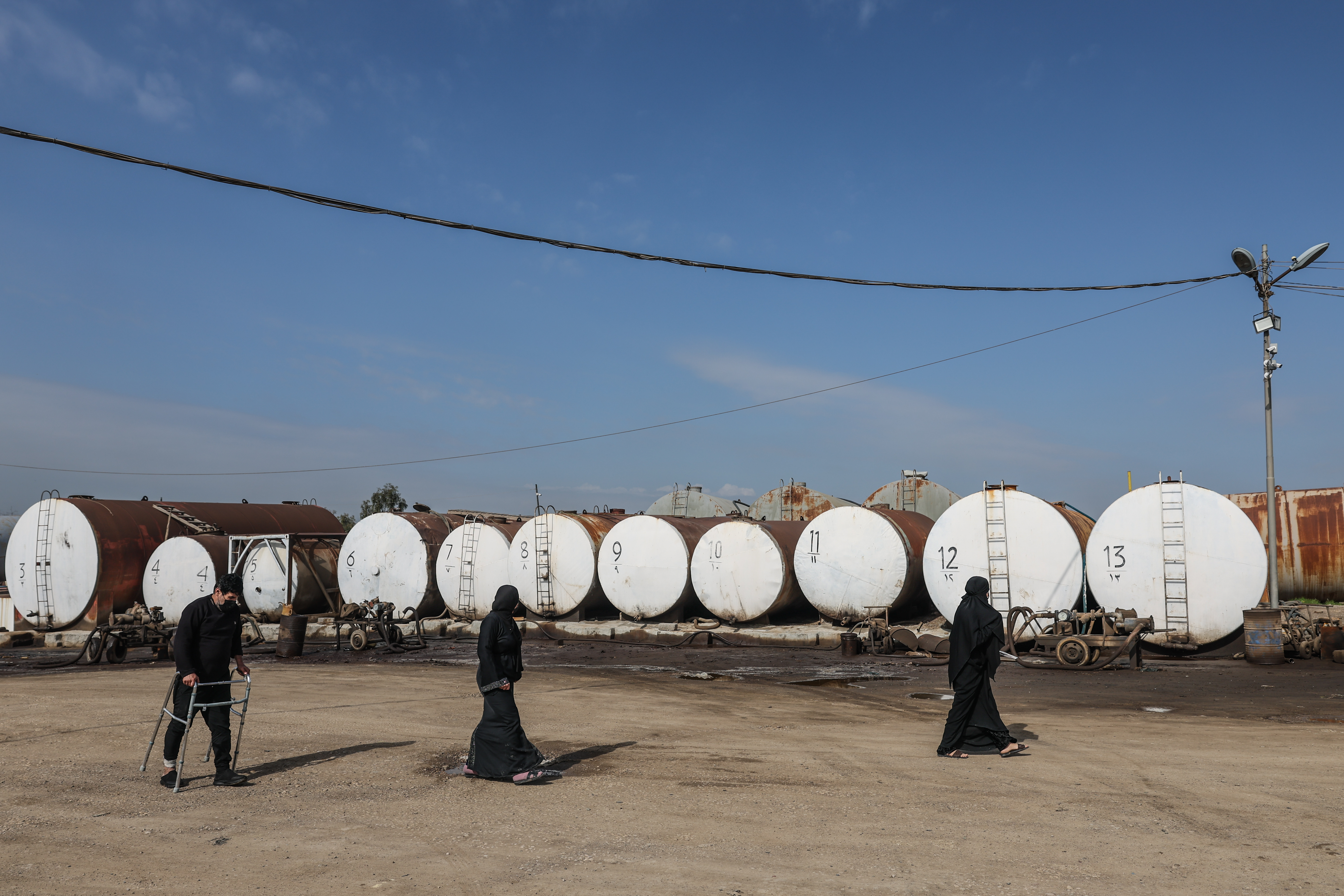 ERBIL, IRAQ - MARCH 17: People walking in front of oil barrels at a market for fuel oil and automotive fuel on March 17, 2026 in Erbil, Iraq. Recent drone attacks in the region have forced some oil refineries here to cease operation, while others continue. More broadly, Iraq, a member of OPEC, has had to sharply reduce oil production as its main export route, through the Strait of Hormuz, has been block due to the war between Iran and the U.S., Israel and their regional allies. On March 12, two oil tankers were attacked in Iraqi waters offshore from its main port of Basrah, allegedly by Iranian forces. Meanwhile, Baghdad and the government of semi-autonomous Iraqi Kurdistan are negotiating to try to increase exports through the Iraq-Turkey Pipeline, which has been a source of political and legal tension. (Photo by Sedat Suna/Getty Images)