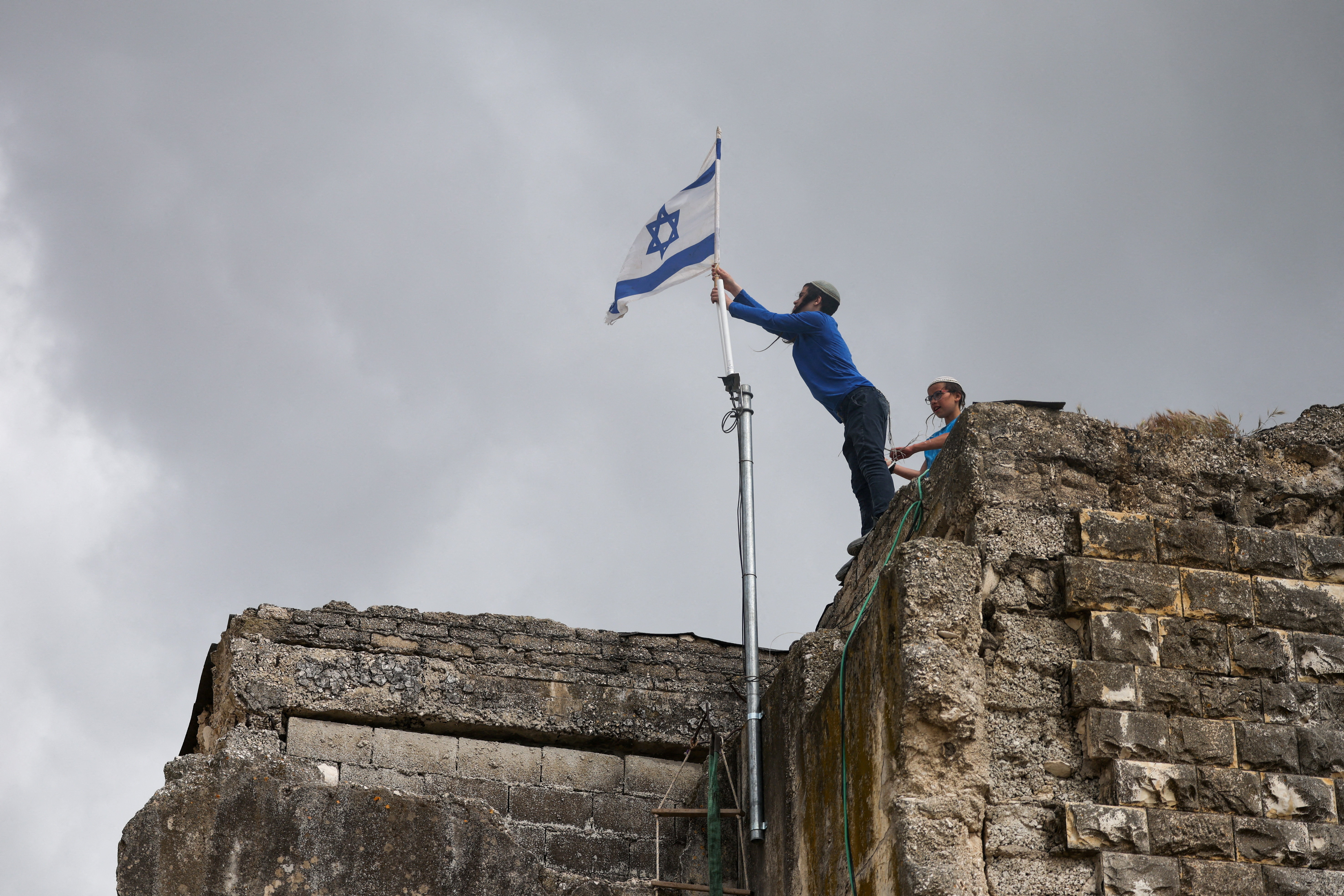 Israeli settlers place an Israeli flag atop a building, on the day of the re-establishment of the settlement of Sa-Nur, which was evacuated as part of Israel’s 2005 disengagement, in Sa-Nur in the Israeli-occupied West Bank, April 19, 2026. REUTERS/Shir Torem TPX IMAGES OF THE DAY