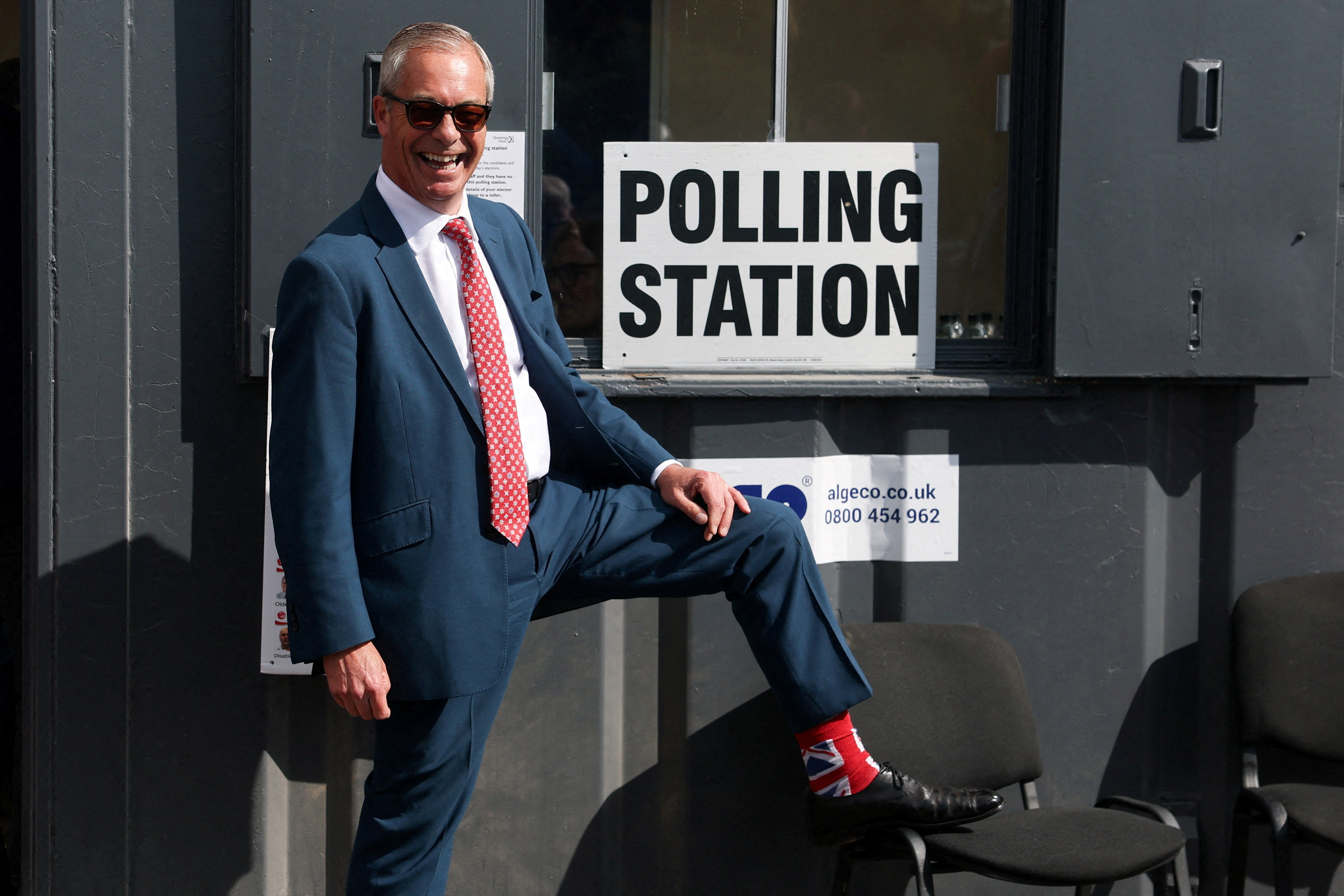 Britain's Reform UK leader Nigel Farage poses outside a polling station