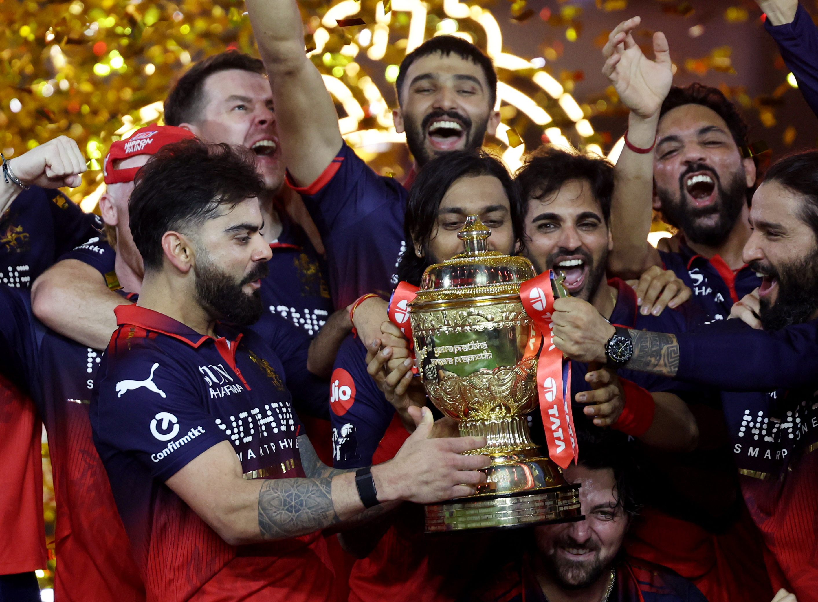 Royal Challengers Bengaluru's Virat Kohli lifts the trophy as he celebrates with teammates after winning the Indian Premier League