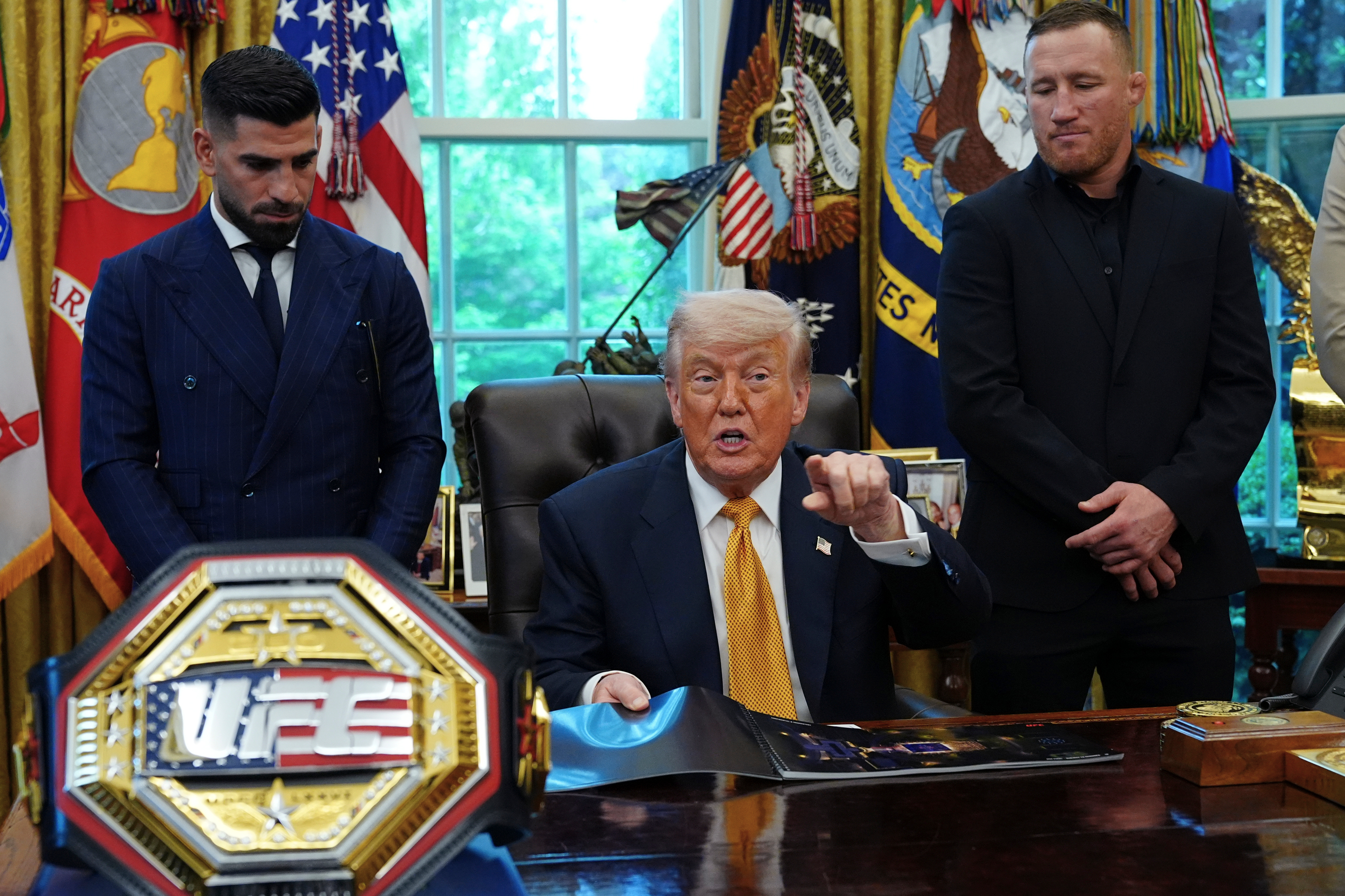 President Donald Trump speaks as Ilia Topuria, left, and Justin Gaethje.