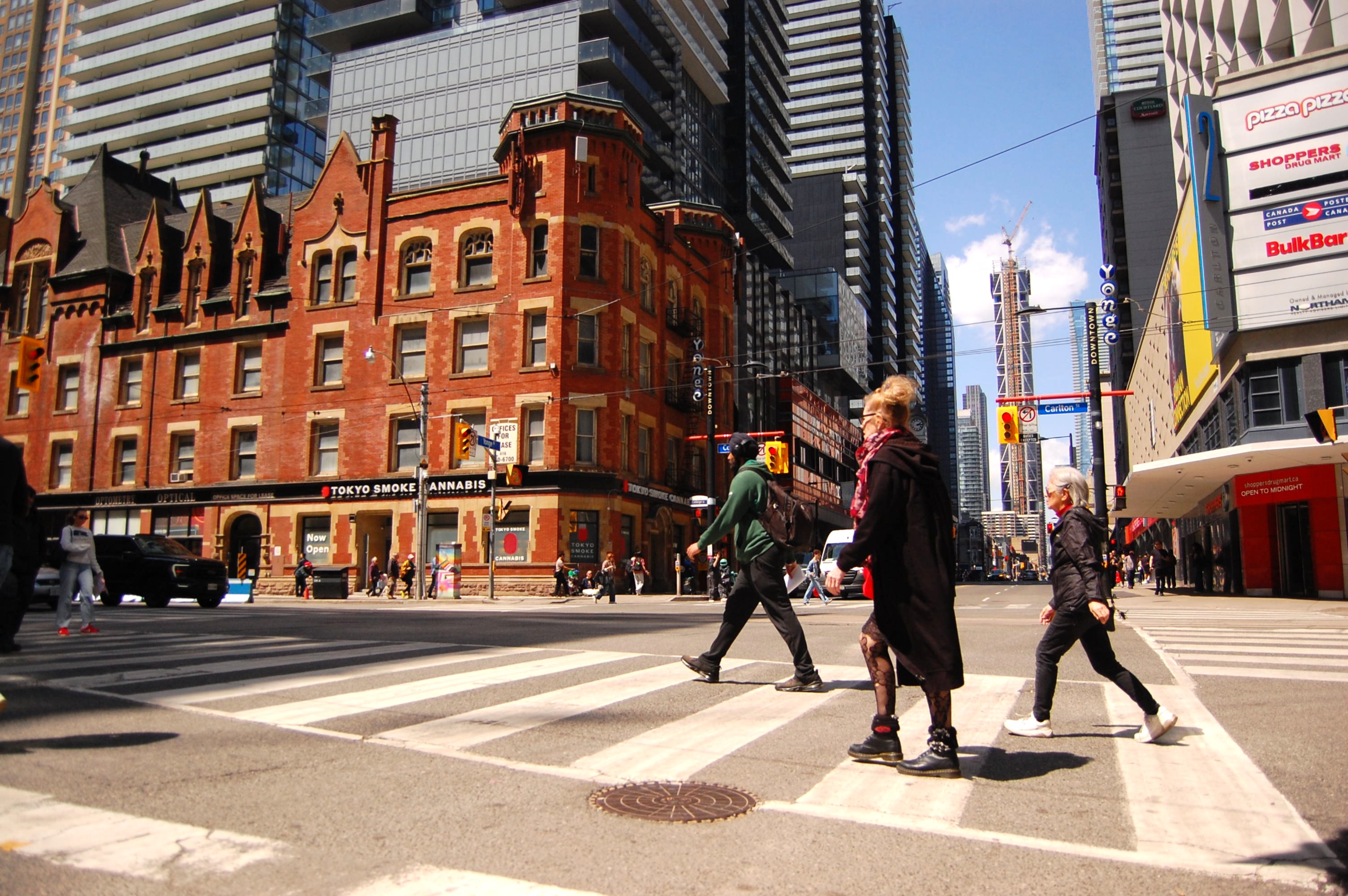 People walk across a street in Toronto, Canada