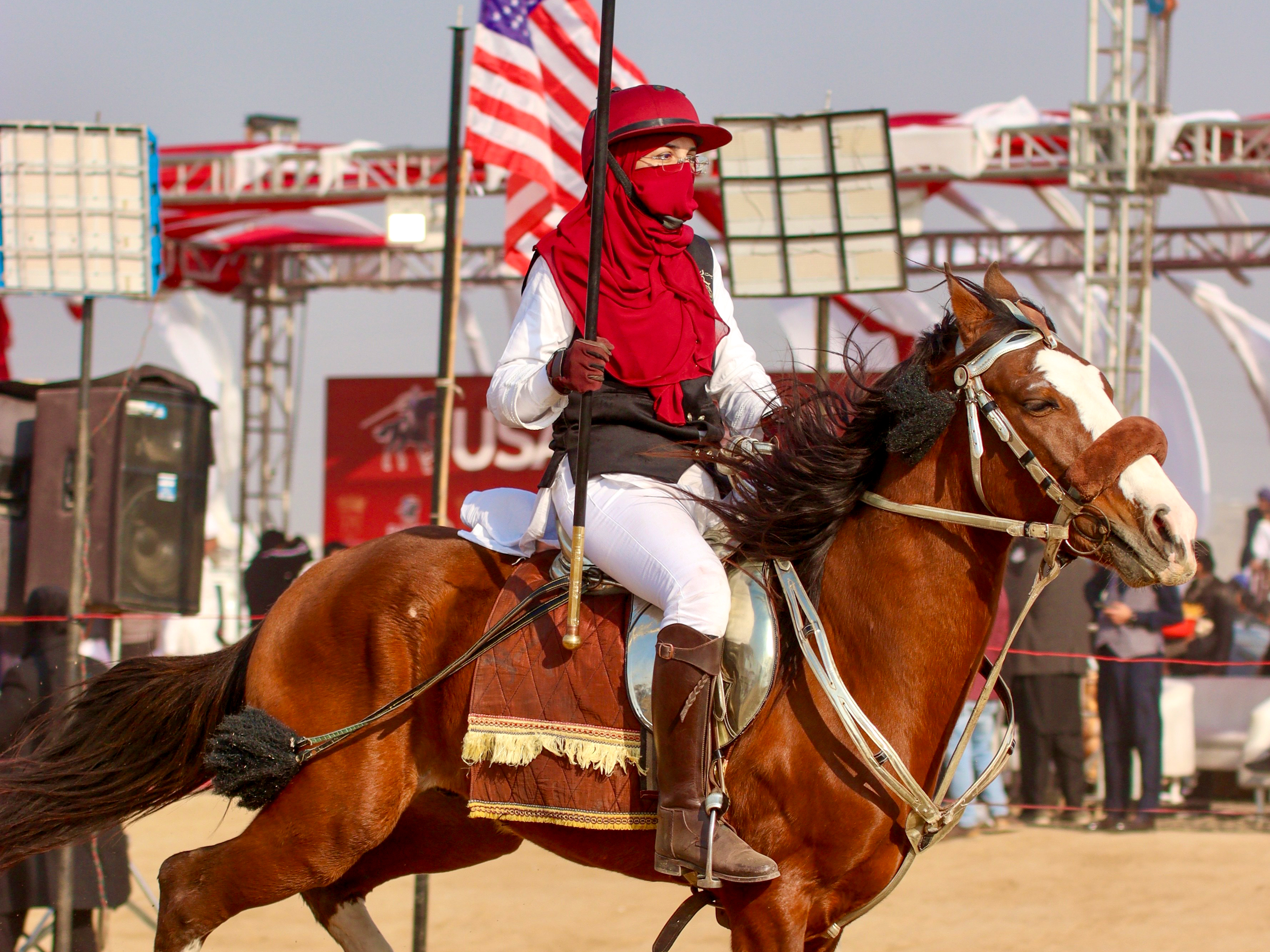 A female rider, Sehrish Awan, straightens her lance as she gears up for competition in a mela organised by a USA-based riding club [Mutee Ur Rehman/ Al Jazeera]