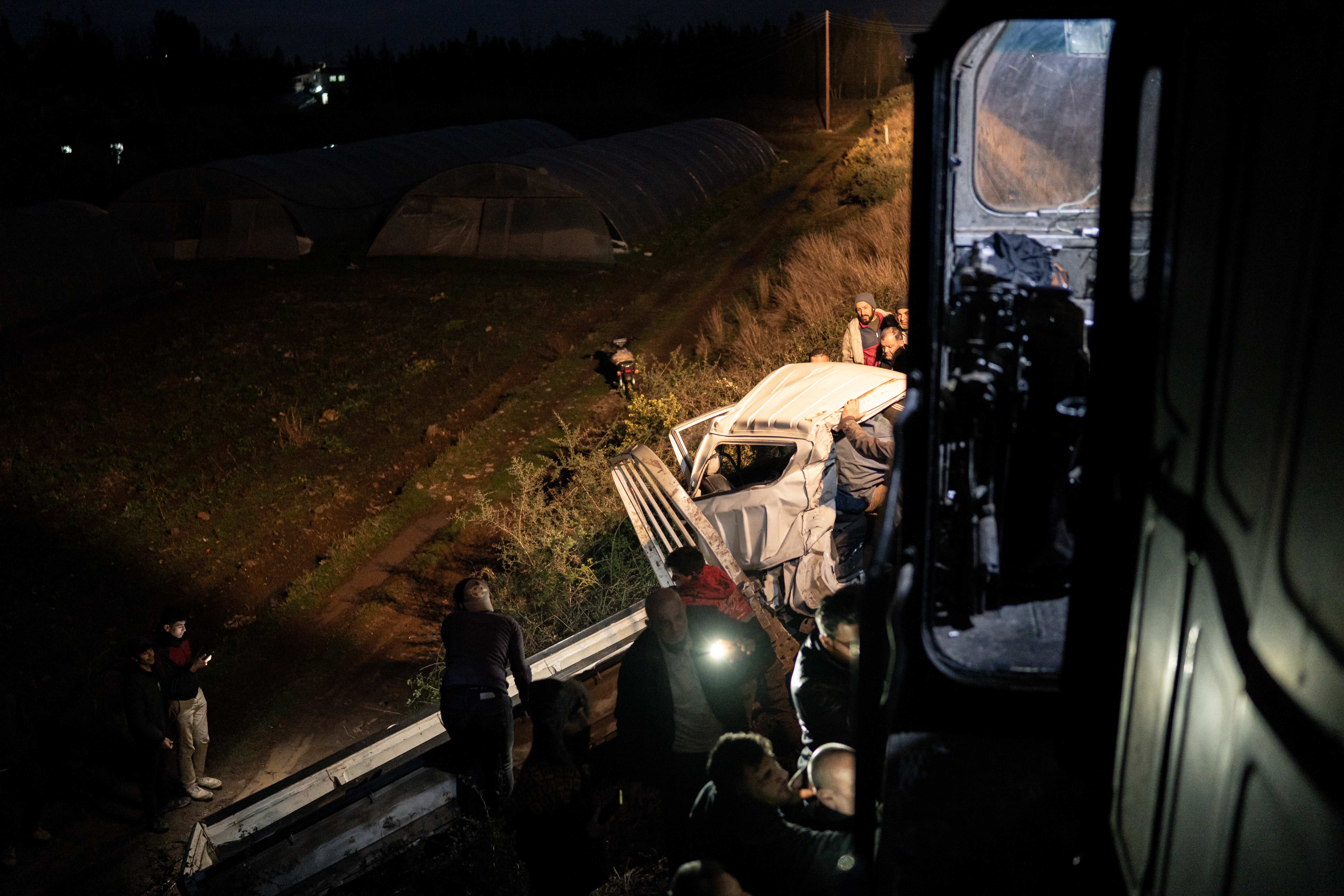 A car is struck by the train at a crossing in the village of Safsafeh, and locals have come to help [Charles Cuau/Al Jazeera]