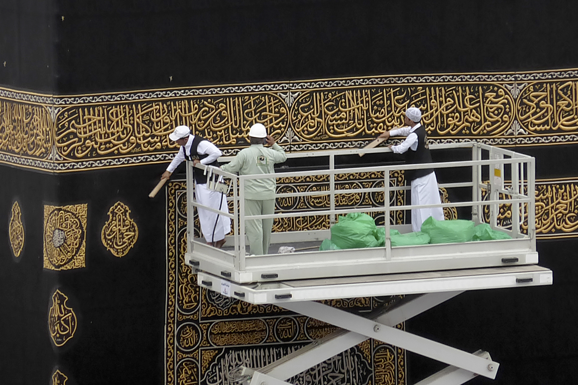 Workers clean the Kiswah, the cloth that covers the Kaaba, the cubic building toward which Muslim believers turn when praying, at the Grand Mosque, in Mecca, Saudi Arabia, Monday, Feb. 24, 2020. (AP Photo/Amr Nabil)