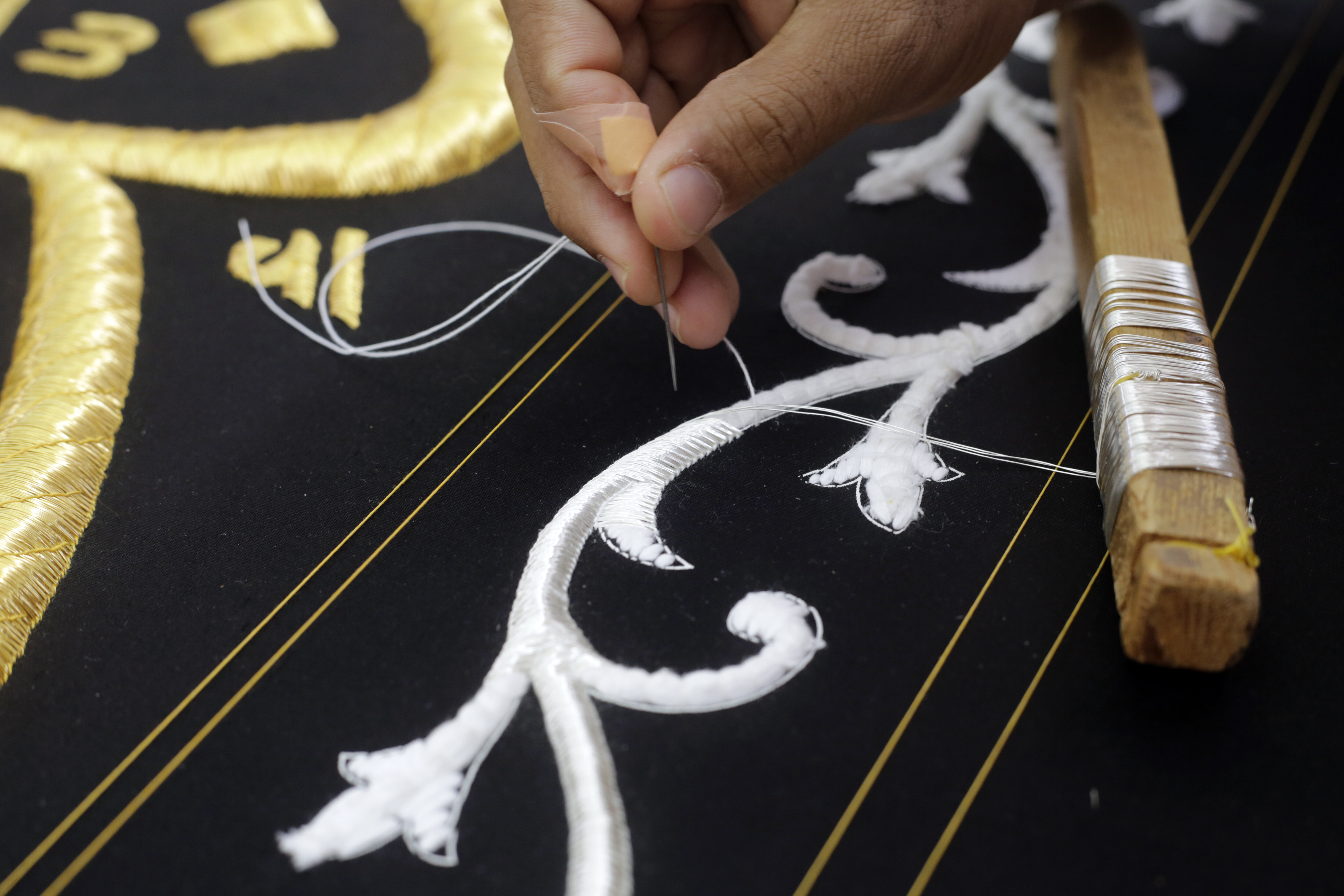 A Saudi man embroiders Islamic calligraphy using either pure silver threads during the final stages in the preparation of a drape, or Kiswa, that covers the Kaaba, a cube-shaped structure at the heart the Grand Mosque, at the Kiswa factory in Mecca, Saudi Arabia, Wednesday, July 14, 2021. The Kiswa covering the Kaaba is changed every year for the Muslim annual Hajj or pilgrimage which will begin this year on July 19. (AP Photo/Amr Nabil)