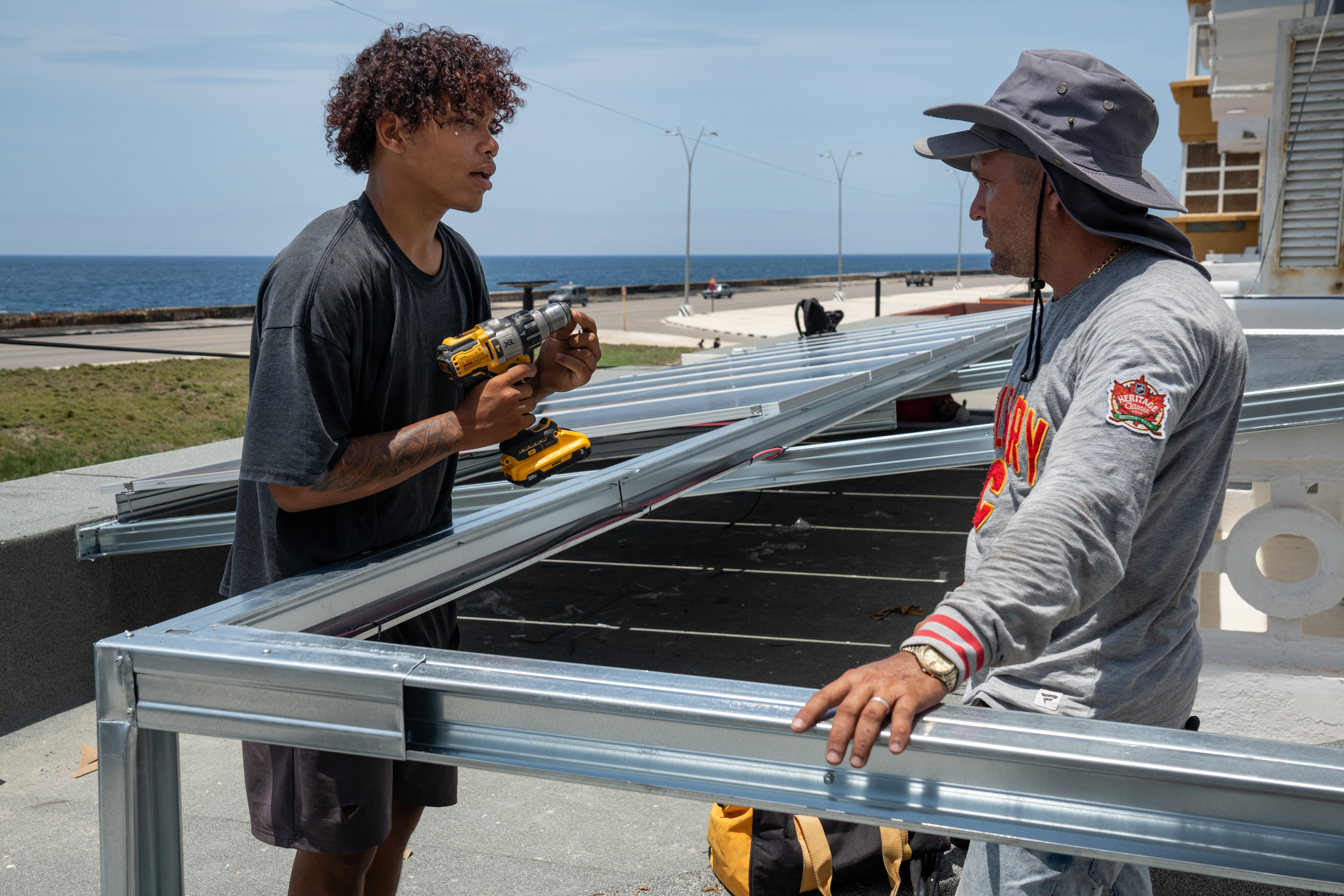 Technicians install solar panels on the roof of the Fuego Lento restaurant along Havana’s Malecón.