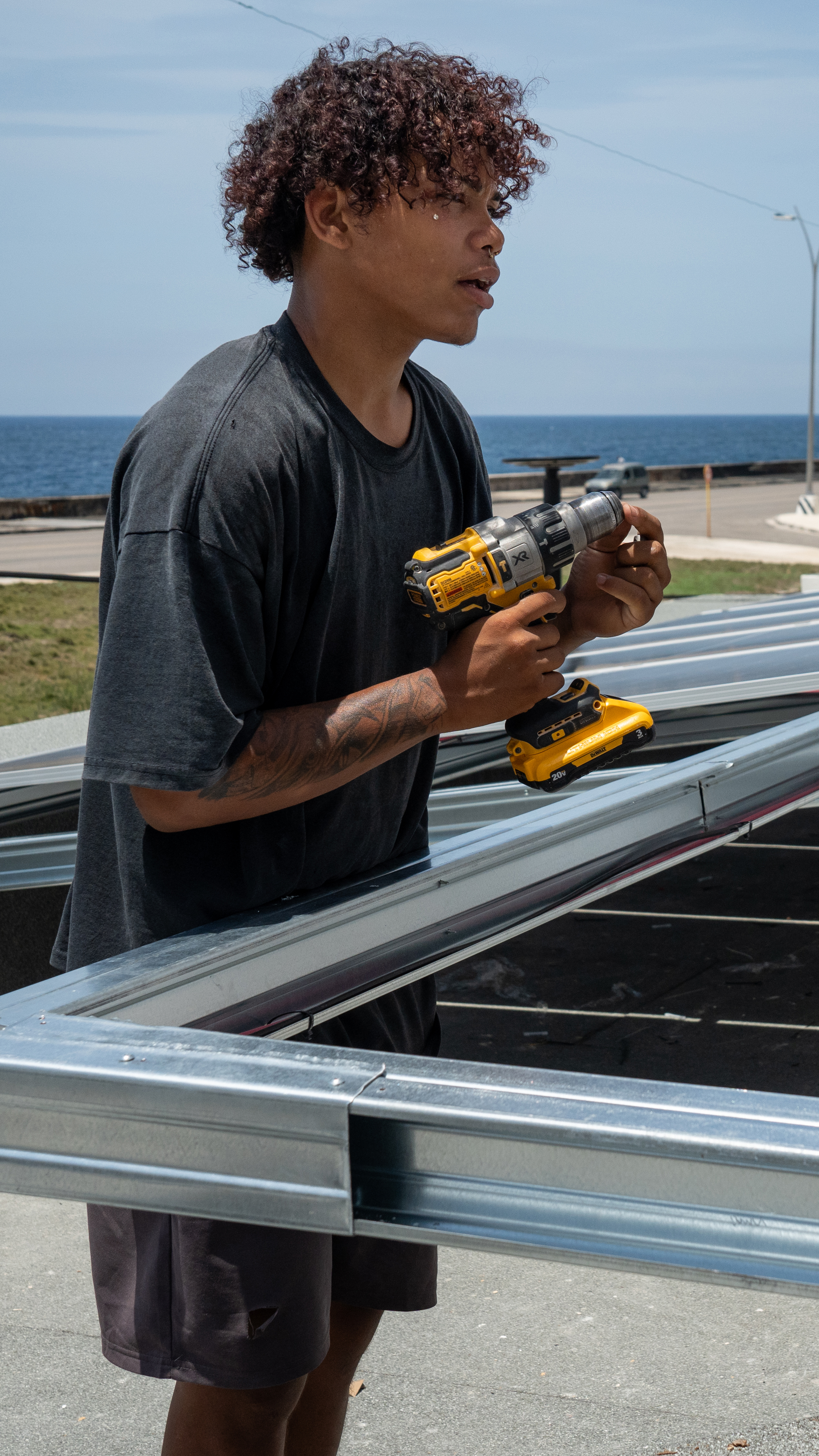 Technicians install solar panels on the roof of the Fuego Lento restaurant along Havana’s Malecón. [Lucien Migne/Al Jazeera]