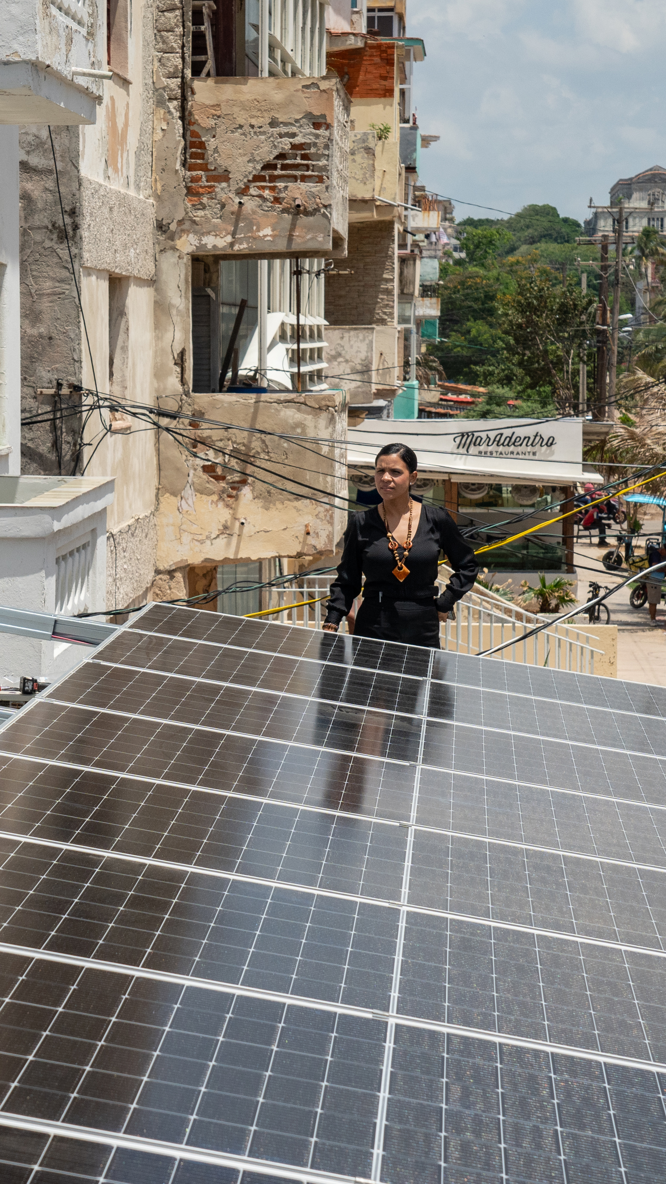 Aris Lopez Torres, owner of the Fuego Lento restaurant, speaks with technician Josecal Duarte during the installation of solar panels on the roof of her business along Havana’s Malecón.