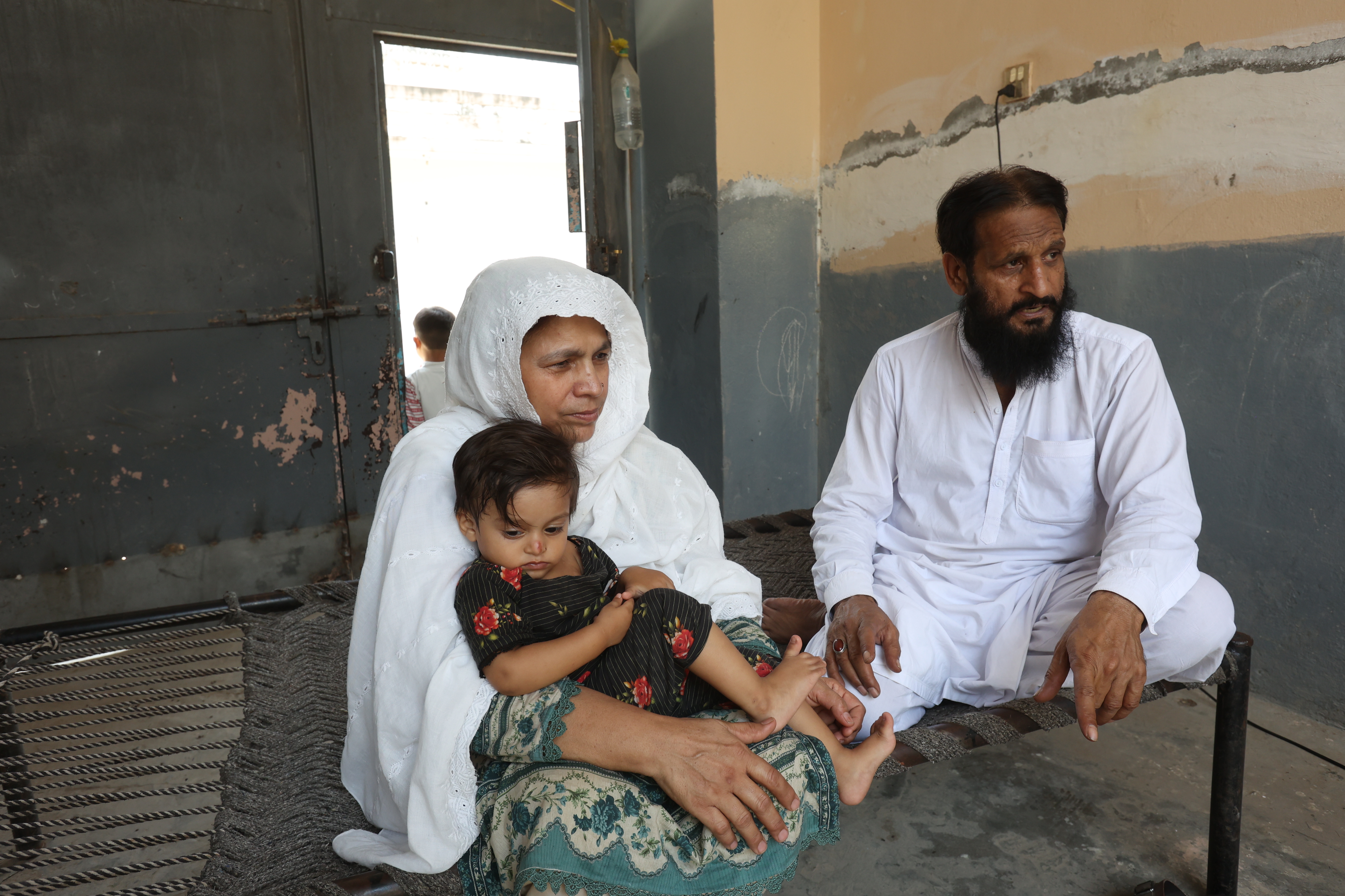 Ansar Majeed sits with her husband, Qari Abdul Majeed Chishti, and one of their grandchildren, reflecting on the family life shaped by decades of football stitching