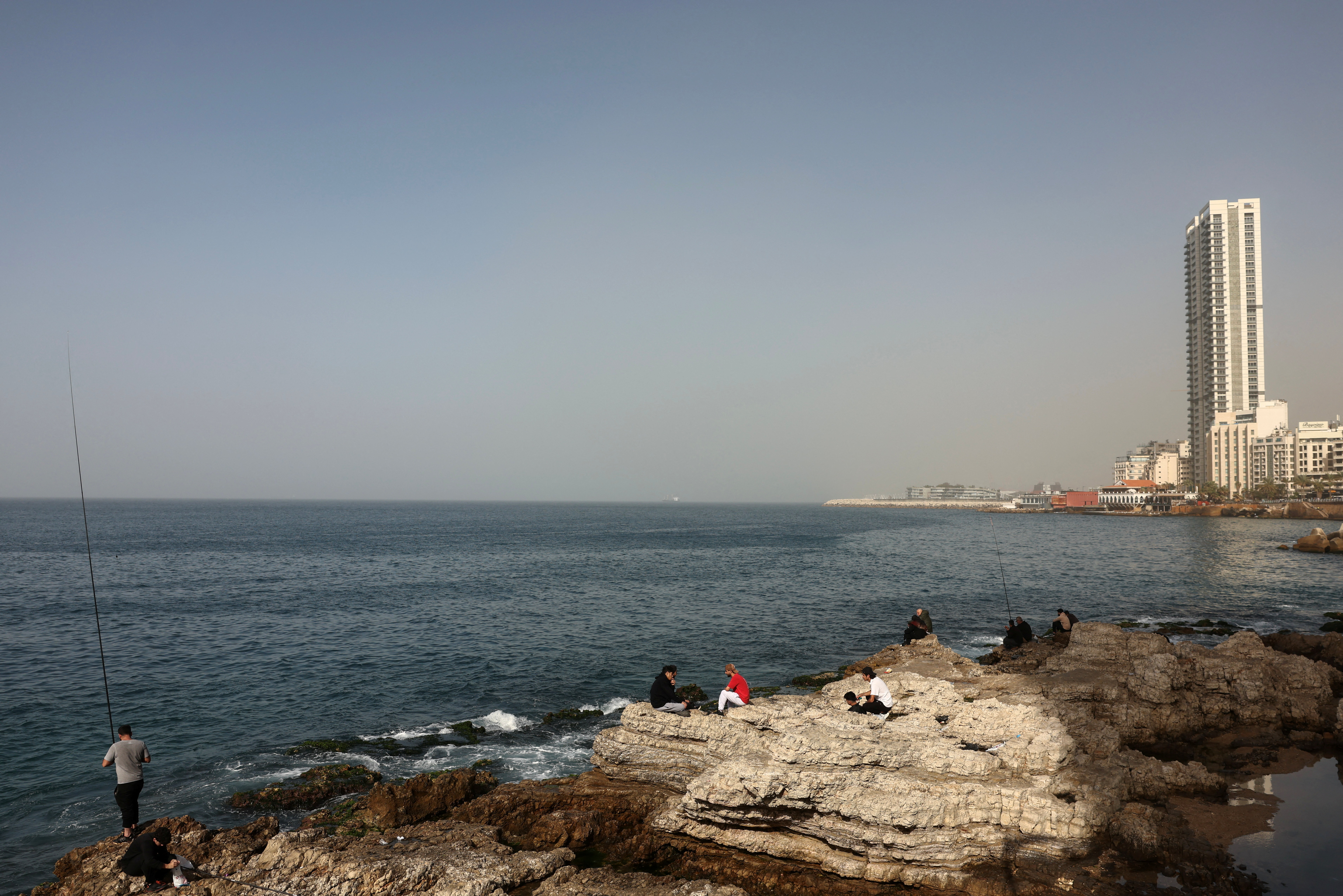 People sit on rocks on the coast of the Mediterranean Sea, amid escalating hostilities between Israel and Hezbollah, as the U.S.-Israeli conflict with Iran continues, in Beirut, Lebanon, April 4, 2026. REUTERS/Yara Nardi