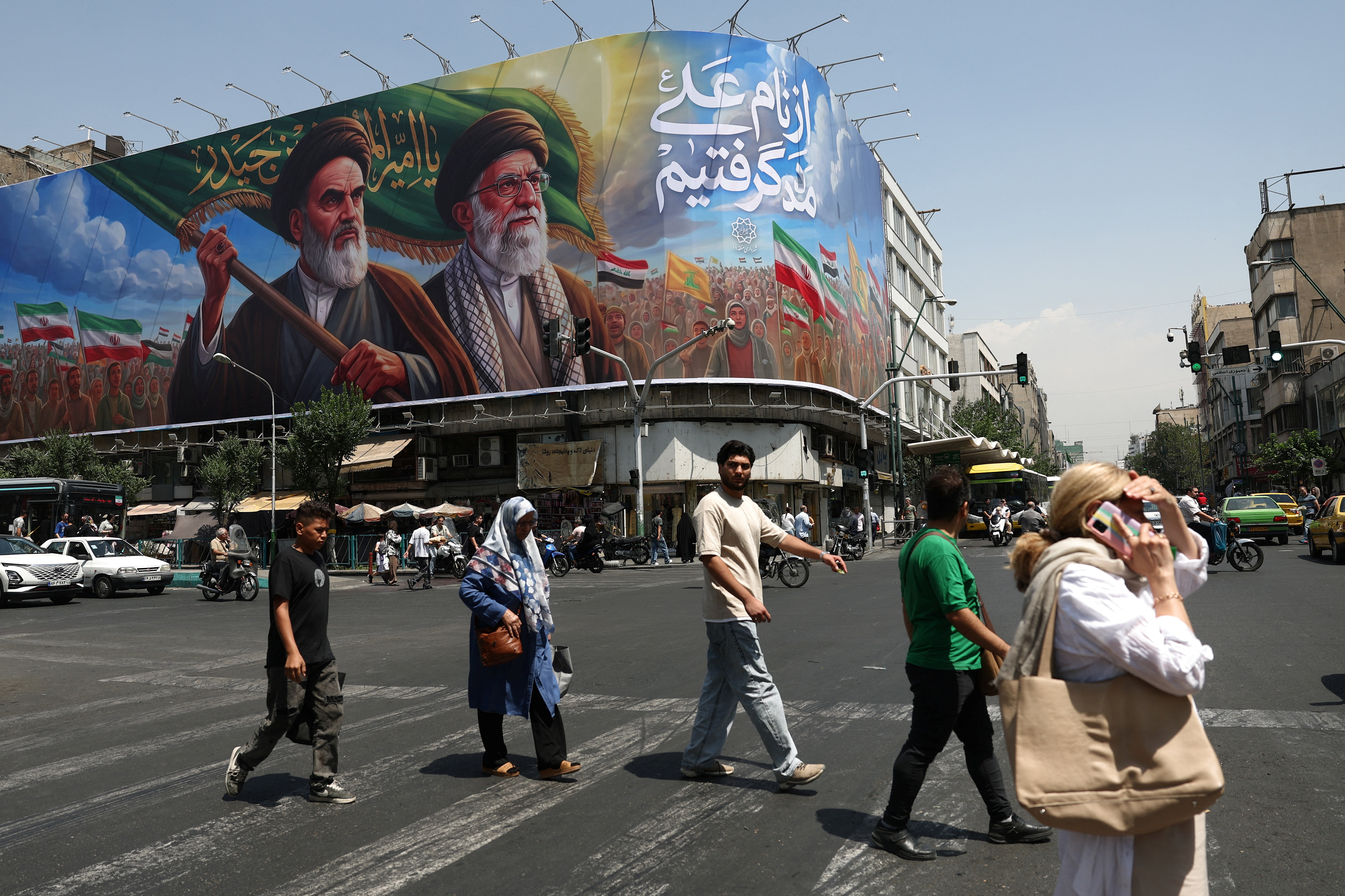 People walk past a billboard in Tehran, Iran