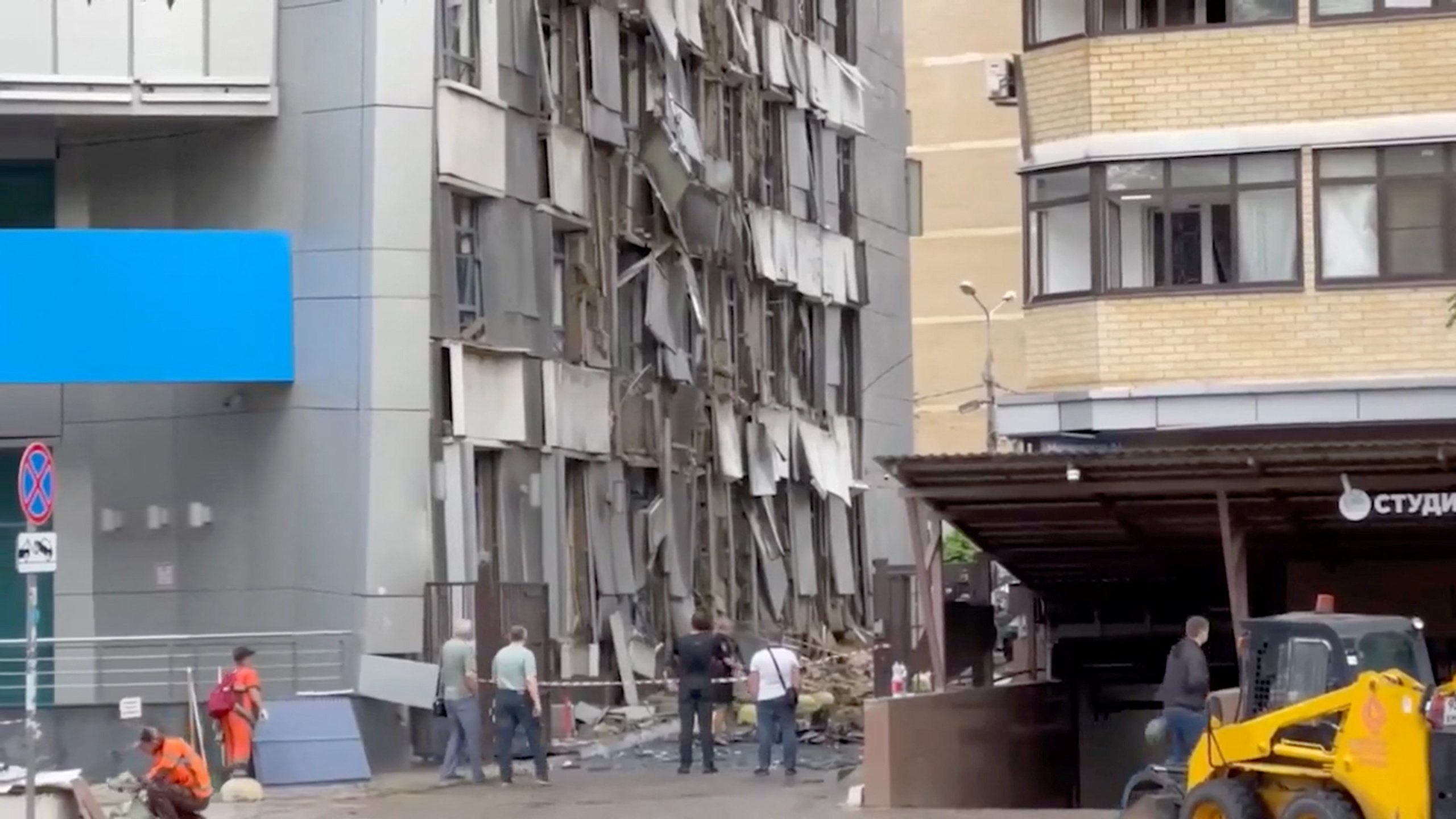 People gather near a residential building damaged during a drone attack,