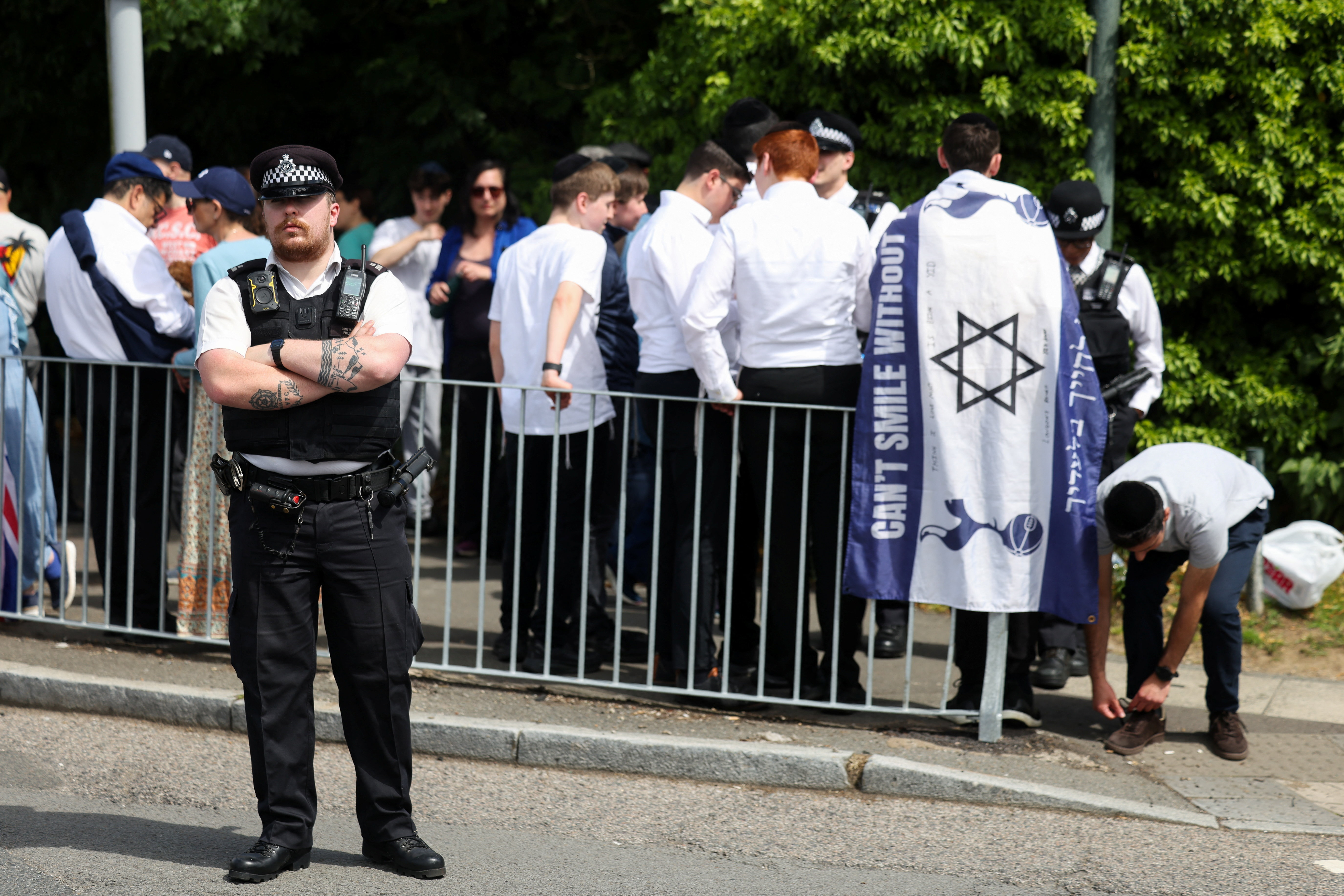 A police officer stands guard near counter-protesters as people from pro-Palestinian activist groups gather near the Edgware United Synagogue, during a demonstration against the "Great Israeli Real Estate Event" organised by real-estate agency, 'My Home in Israel', which markets property in Israeli settlements in the occupied West Bank, in London, Britain, June 14, 2026. REUTERS/Toby Shepheard