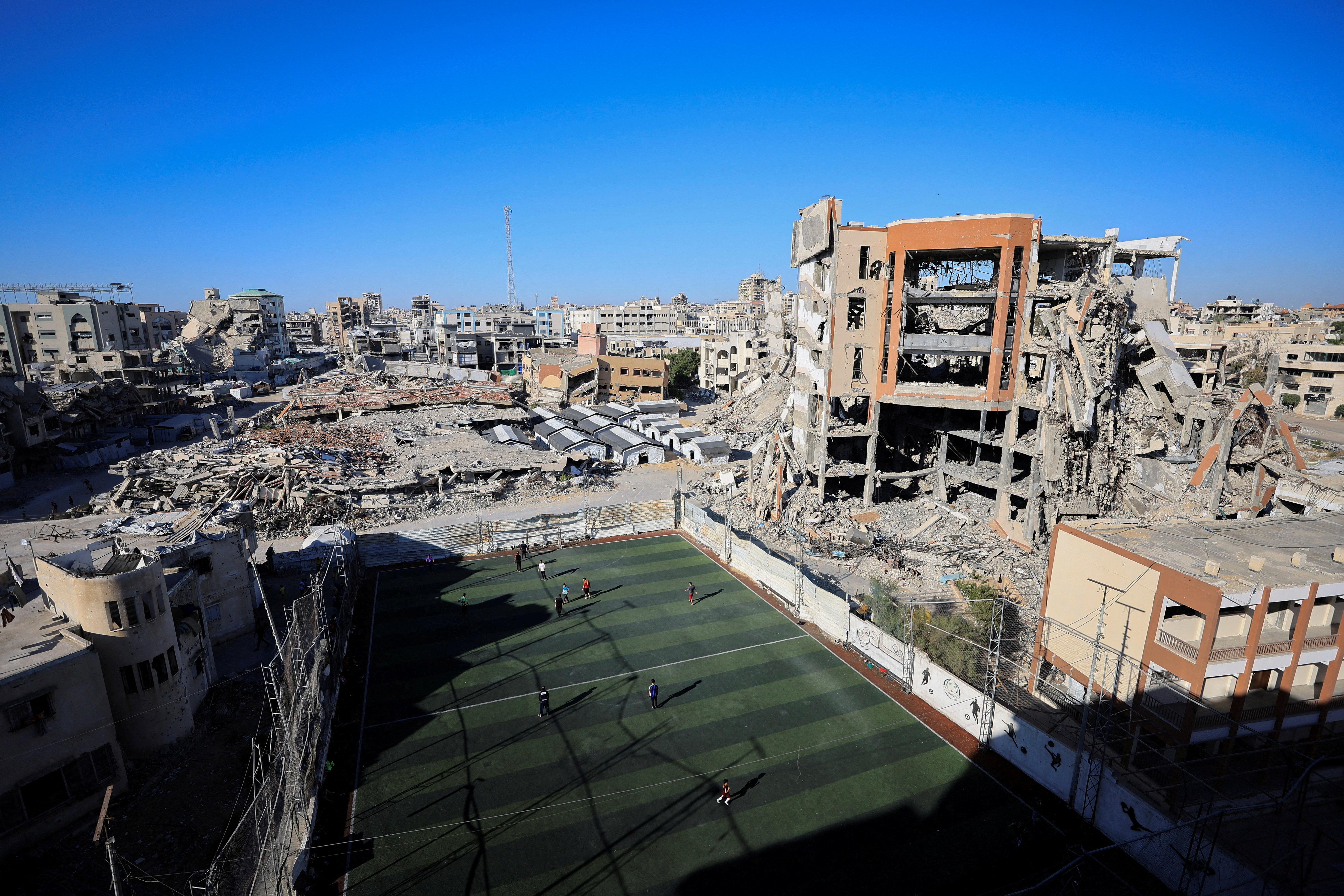 A general view of Palestinians playing soccer on a pitch amid destroyed buildings in Gaza City, June 13, 2026.