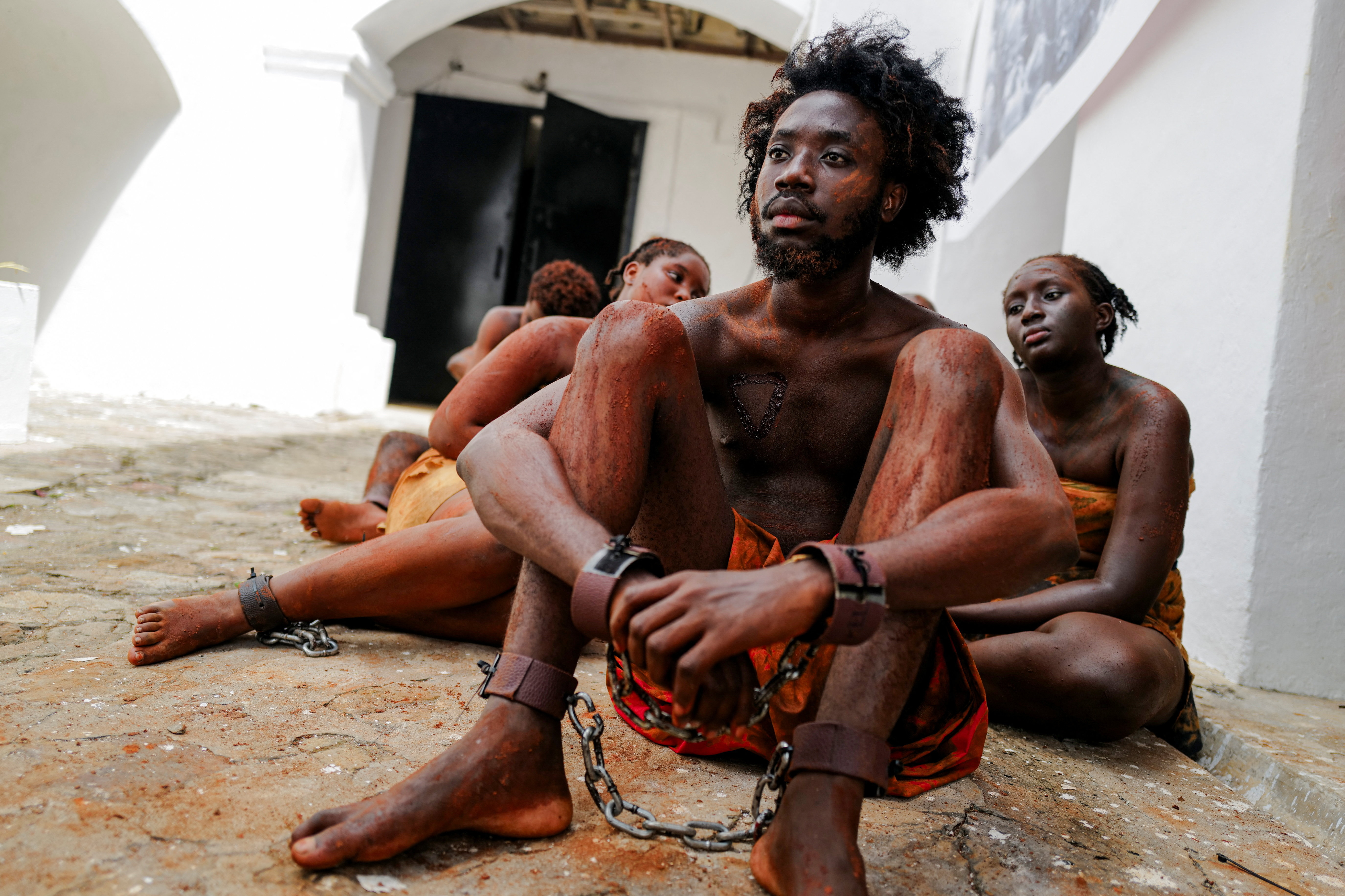 Performers present a reenactment of the trans-Atlantic slave trade at the Christiansborg Castle, a former slave post, during a high-level consultative conference on the next steps to the landmark United Nations resolution on the trafficking of enslaved Africans, in Accra, Ghana [Francis Kokoroko/Reuters]