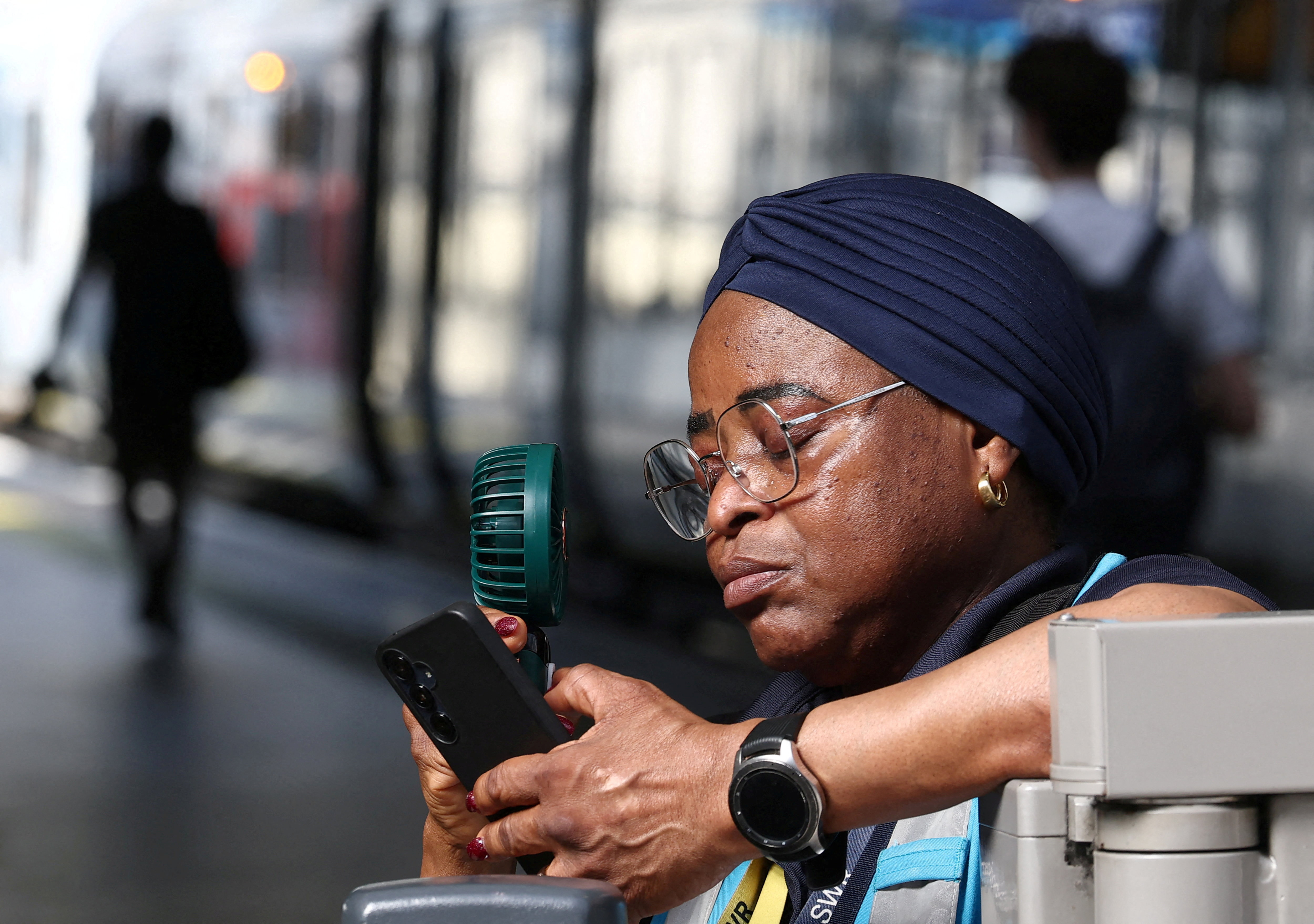 A railway revenue protection officer uses a fan to cool down on a rail platform as Britain experiences record temperatures disrupting schools and transport networks, at Waterloo Station in London, Britain, June 24, 2026. REUTERS/Toby Melville TPX IMAGES OF THE DAY