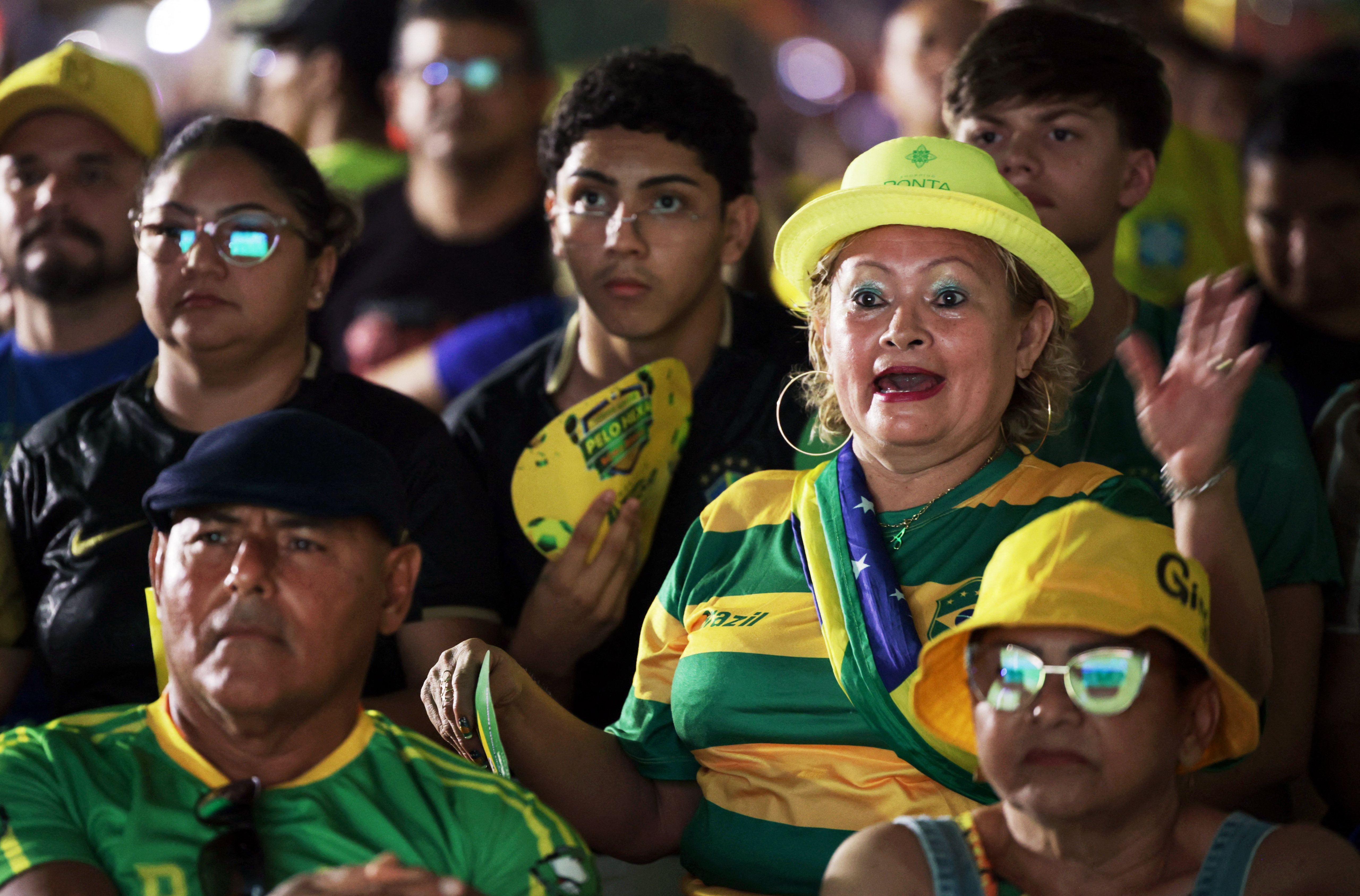 Brazil football fans in a crowd react with tense expressions as they watch a match on a screen in Manaus, Brazil