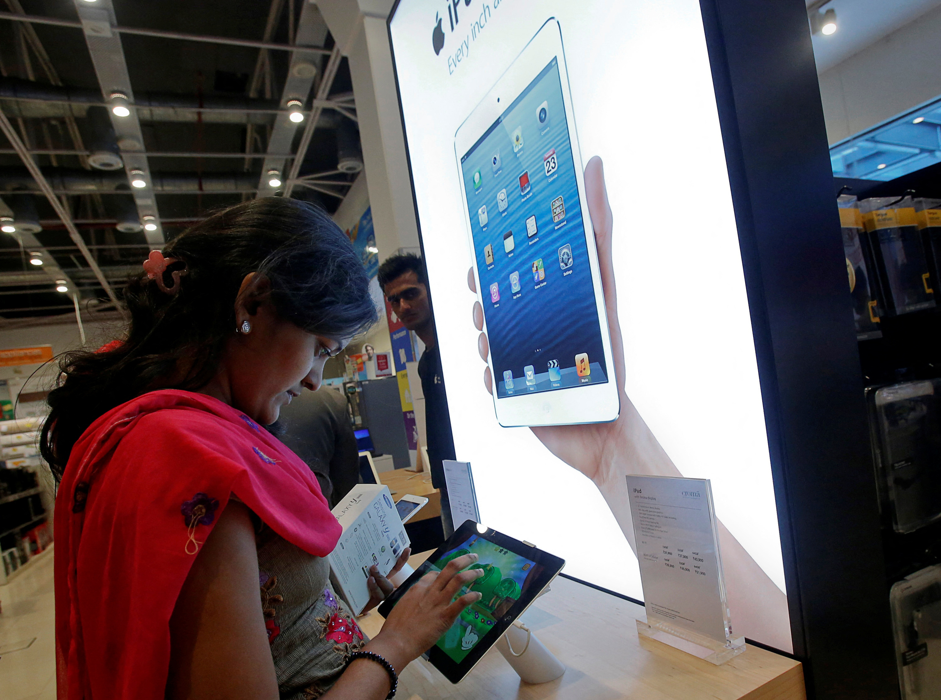 FILE PHOTO: A customer tries out an Apple iPad Mini in the Apple specialty section of a Croma retail store in Mumbai February 22, 2013. REUTERS/Vivek Prakash/File Photo