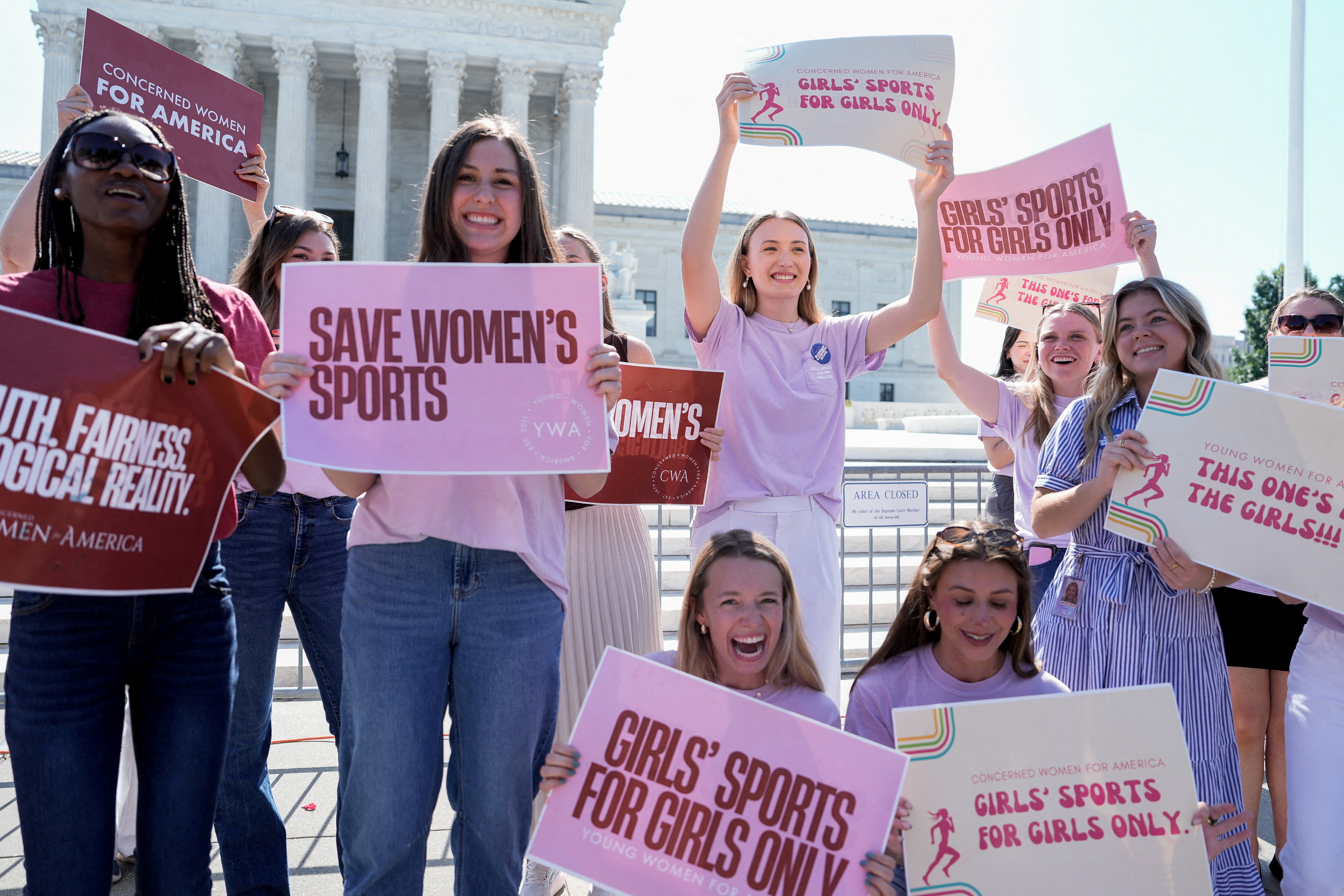 Women hold placards as they celebrate the U.S. Supreme Court's final rulings of its nine-month term, including a decision that cleared the way for states to impose restrictions on transgender student athletes, upholding laws in West Virginia and Idaho banning them from female sports teams, in Washington, D.C., U.S., June 30, 2026. [Cheney Orr/Reuters]