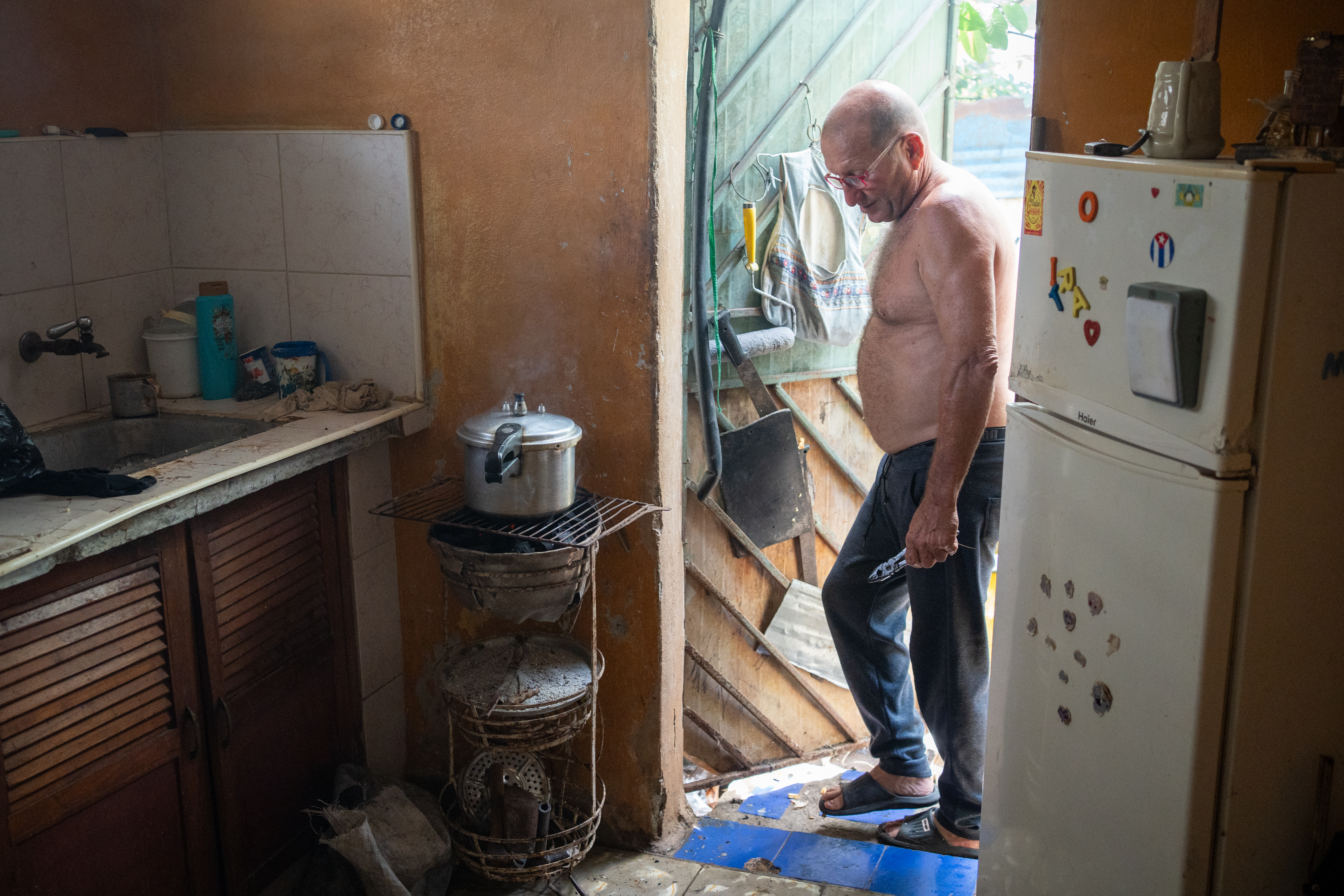 Idalberto Espinoza, 60, cooks chicken over a charcoal stove at his home in Cotorro, on the outskirts of Havana.