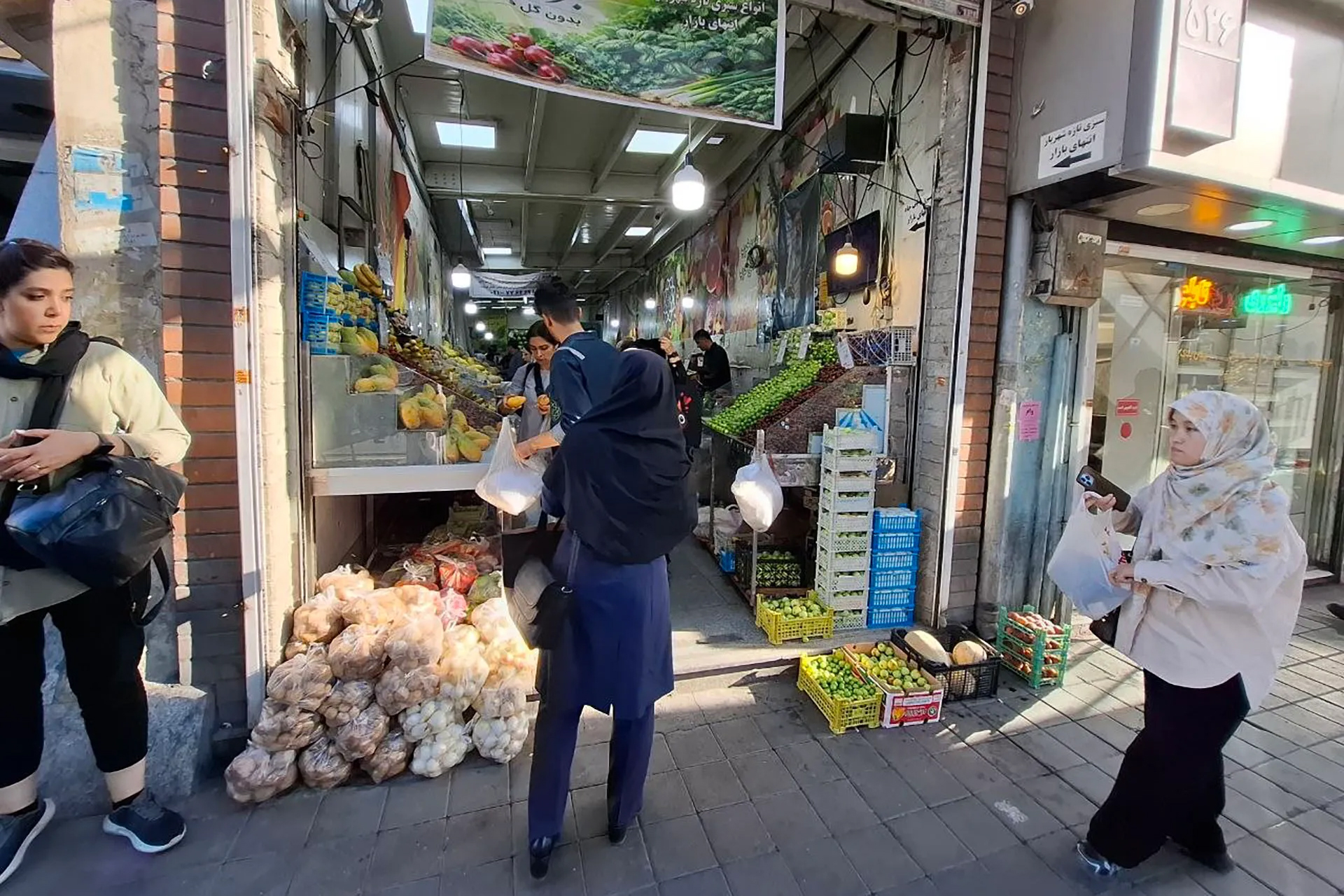 Shoppers browse for fresh produce at a market in Tehran. Consumers report that despite the rial's recovery, prices for basic food items and everyday goods remain stubbornly high.