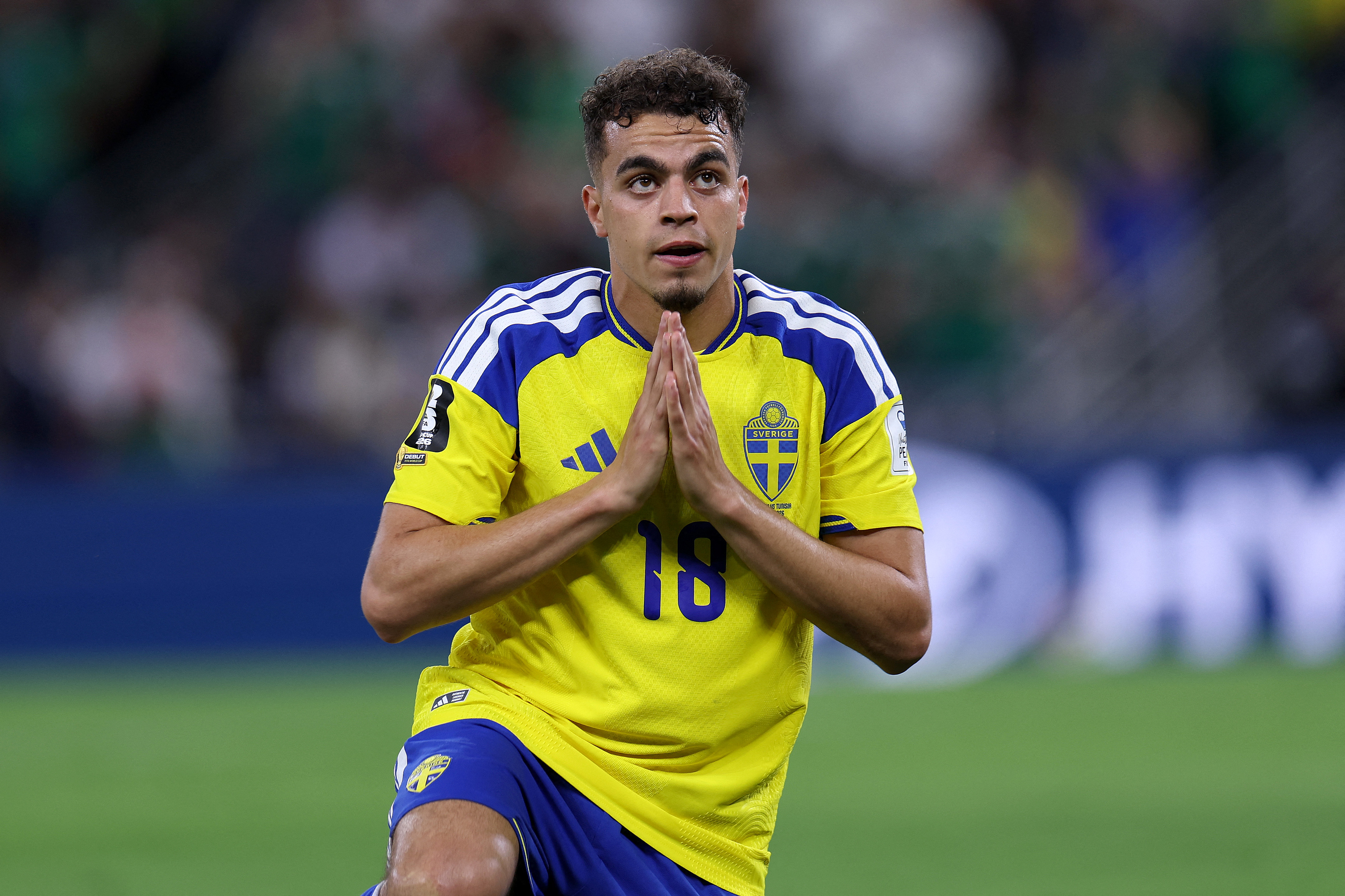 Sweden's midfielder #18 Yasin Ayari kneels and holds his hands together on the pitch.