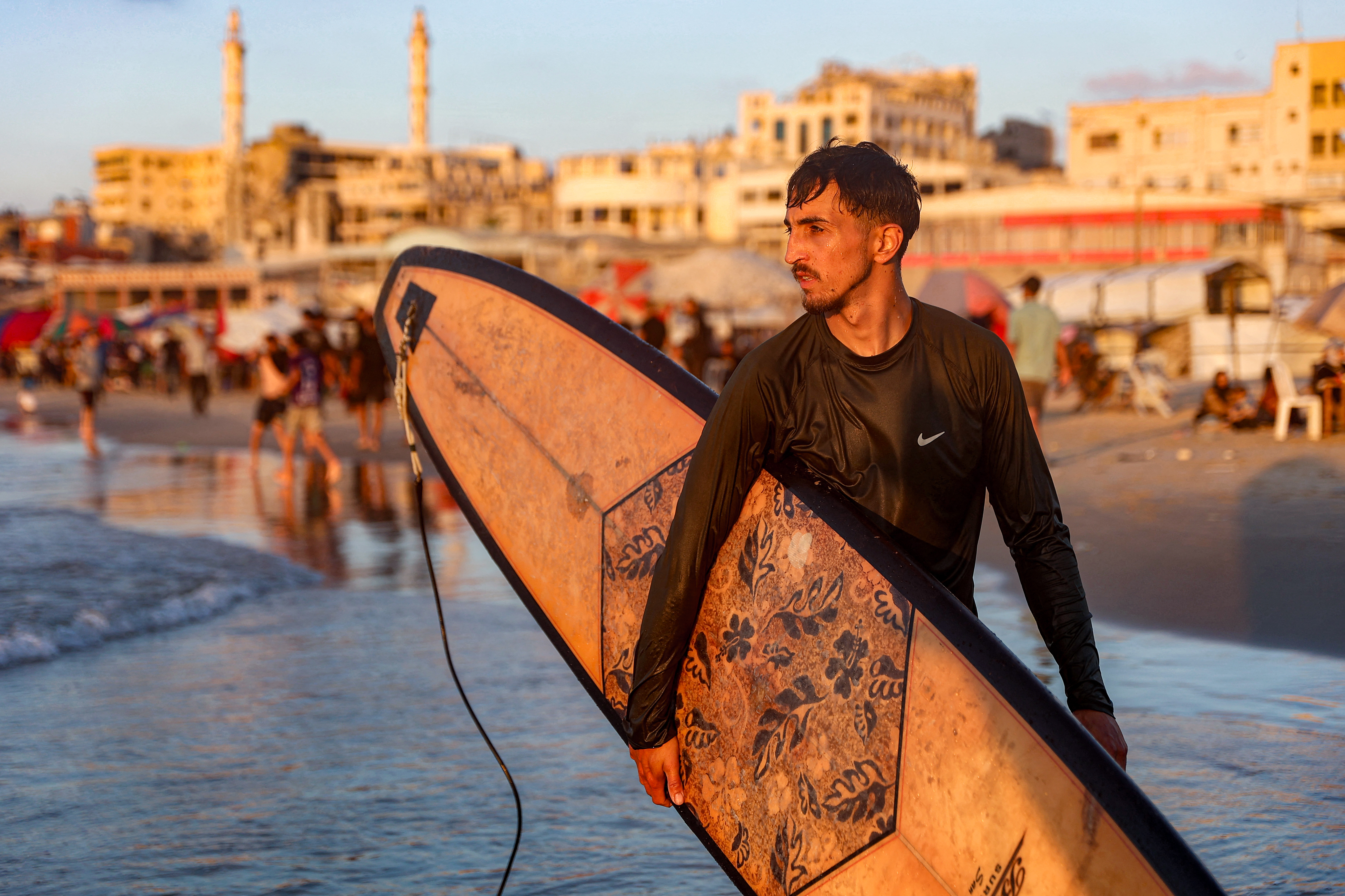 A man carries a surfboard near the sea.