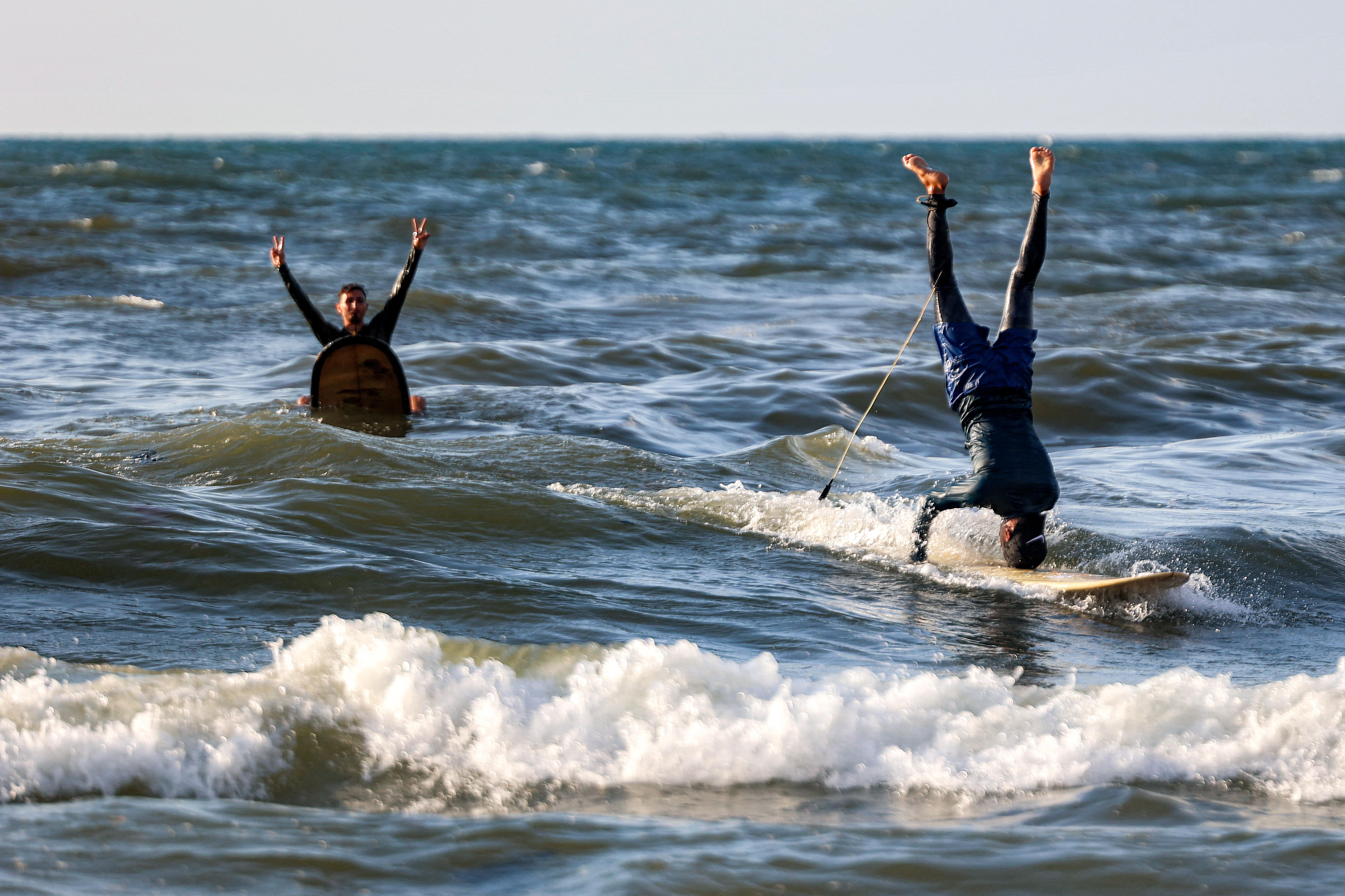 Gaza surfers perform tricks on their surfboards in the Mediterranean Sea off a beach in Gaza City