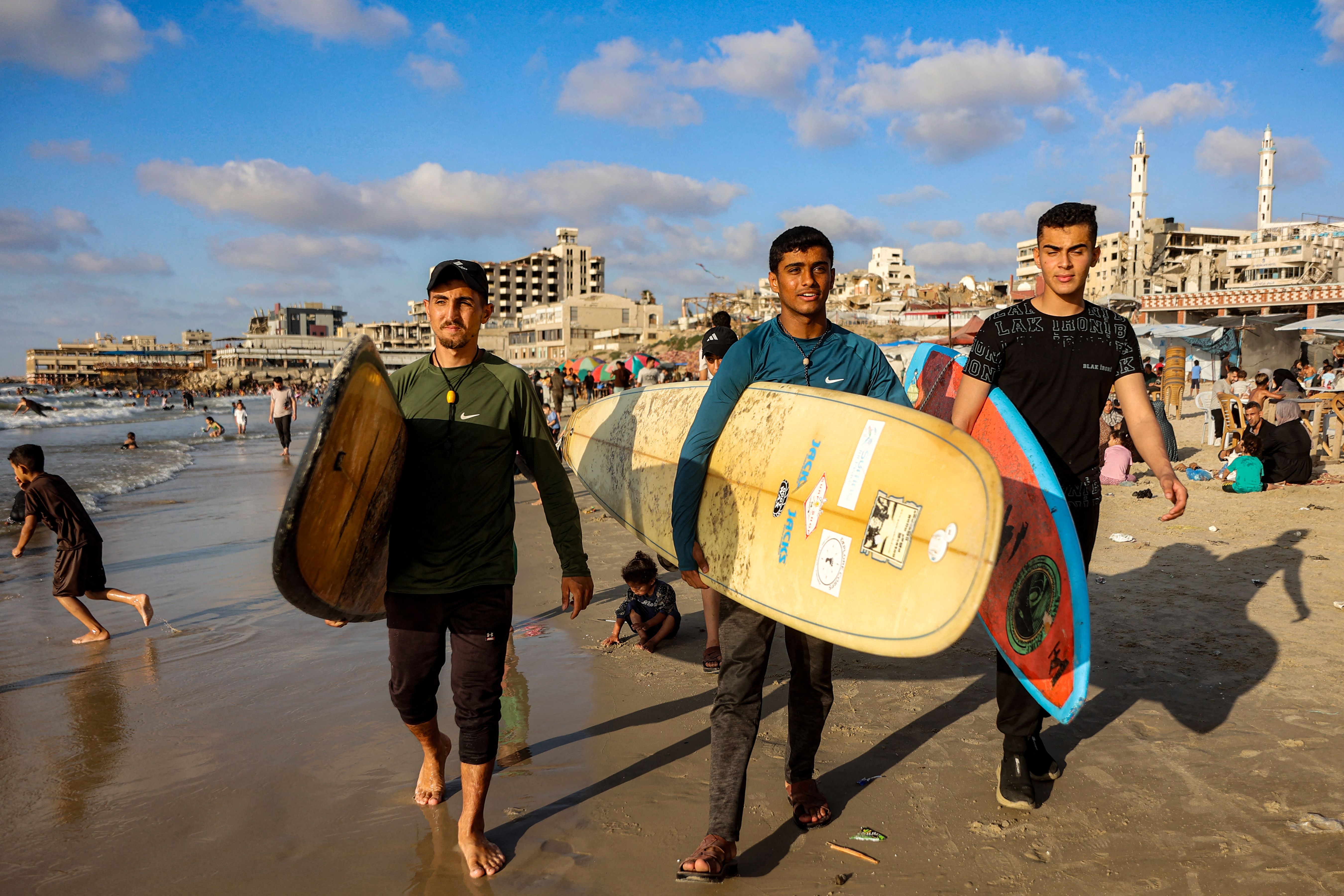 Gaza surfers Tahseen Abu Assi (left), Abdel Rahim Ustadh (centre) and Khalil Abu Jiyab carry their surfboards along a beach by the Mediterranean sea in Gaza City
