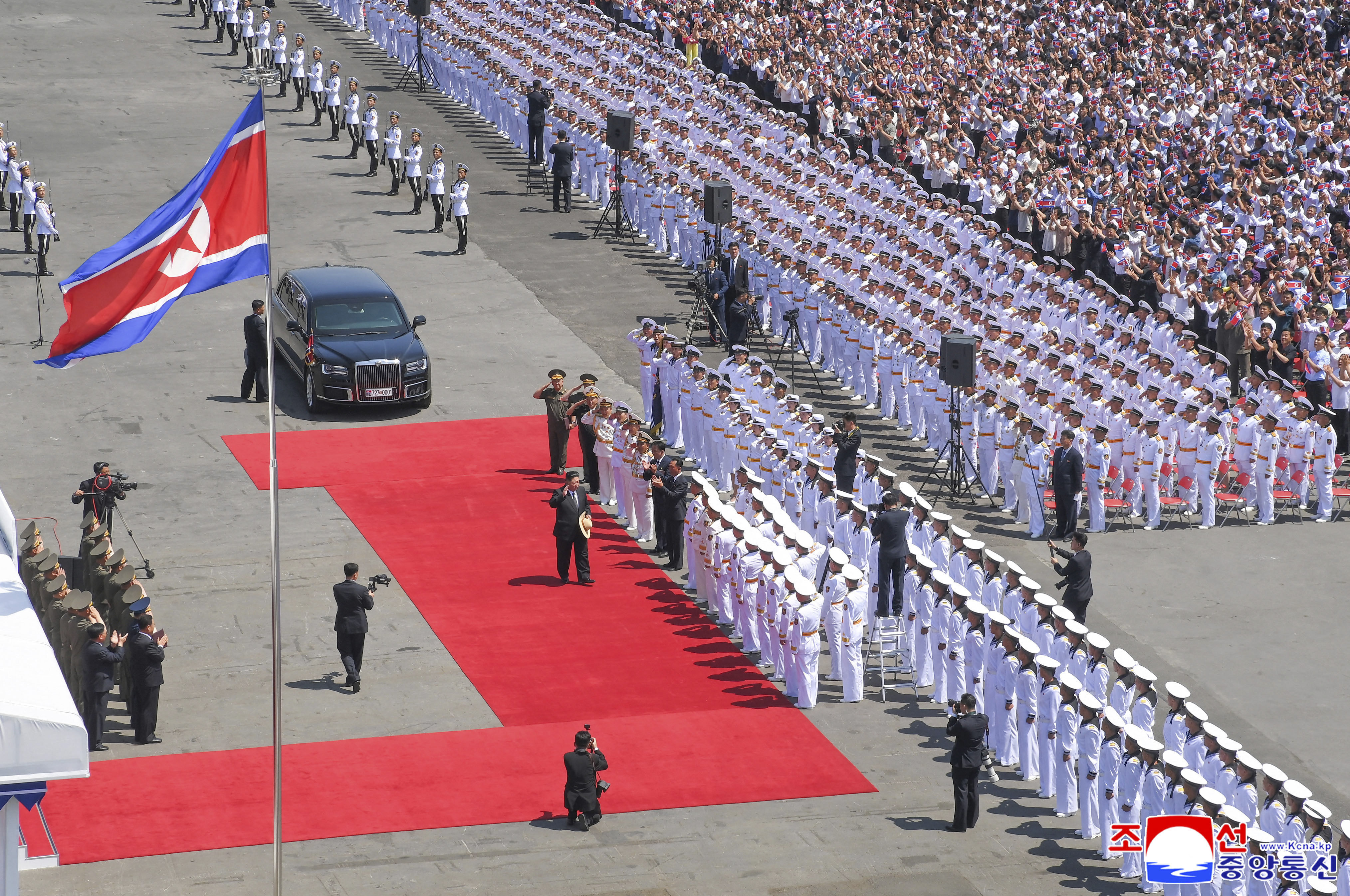 Kim Jong Un stands among uniformed military officials at a naval commissioning ceremony.