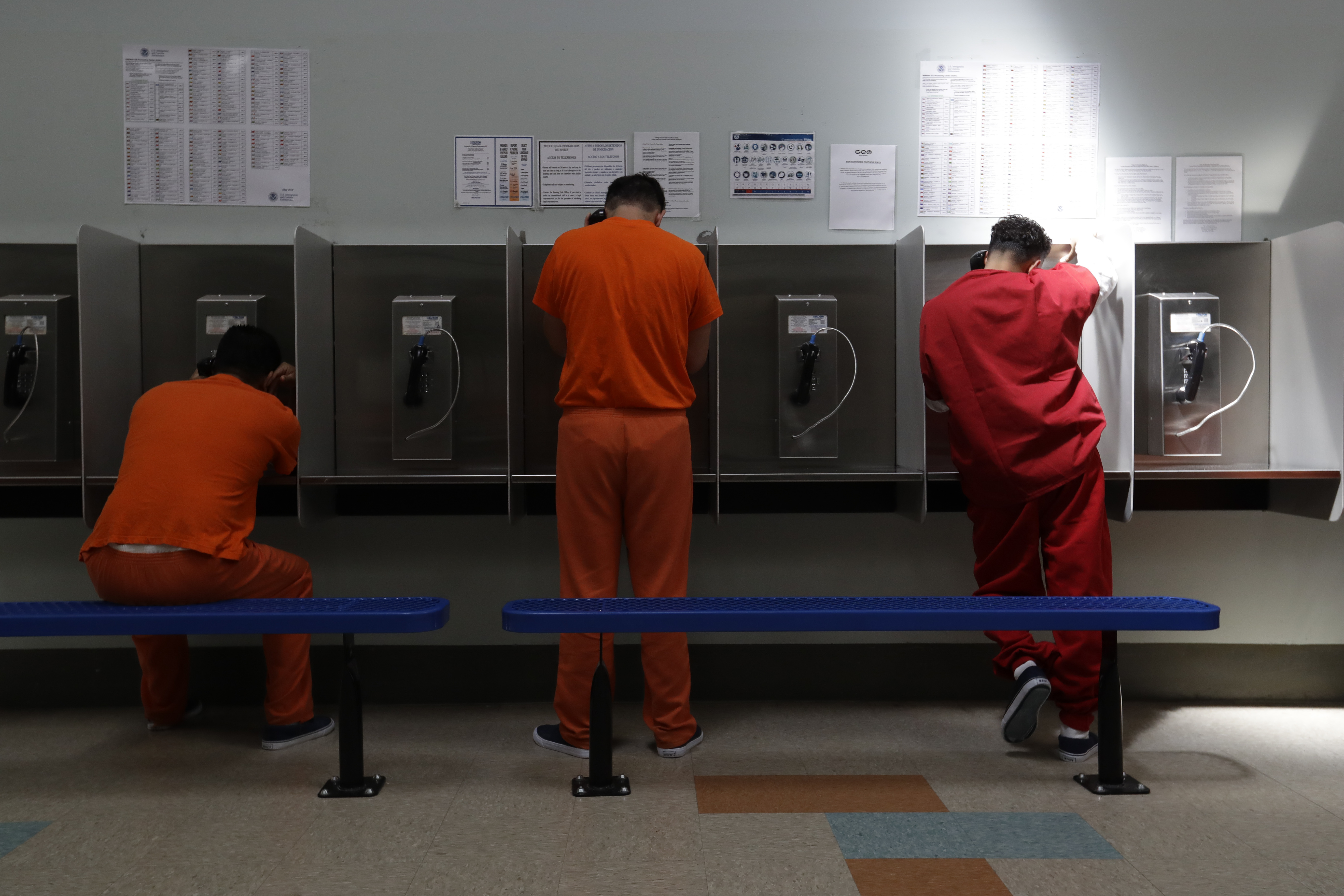 FILE - Detainees talk on telephones at the Adelanto ICE Processing Center in Adelanto, Calif., Aug. 28, 2019. A federal appeals court on Tuesday, April 26, 2022, agreed to reconsider a ruling that rejected the state’s first-in-the-nation ban on for-profit private prisons and immigration detention facilities. (AP Photo/Chris Carlson, File)