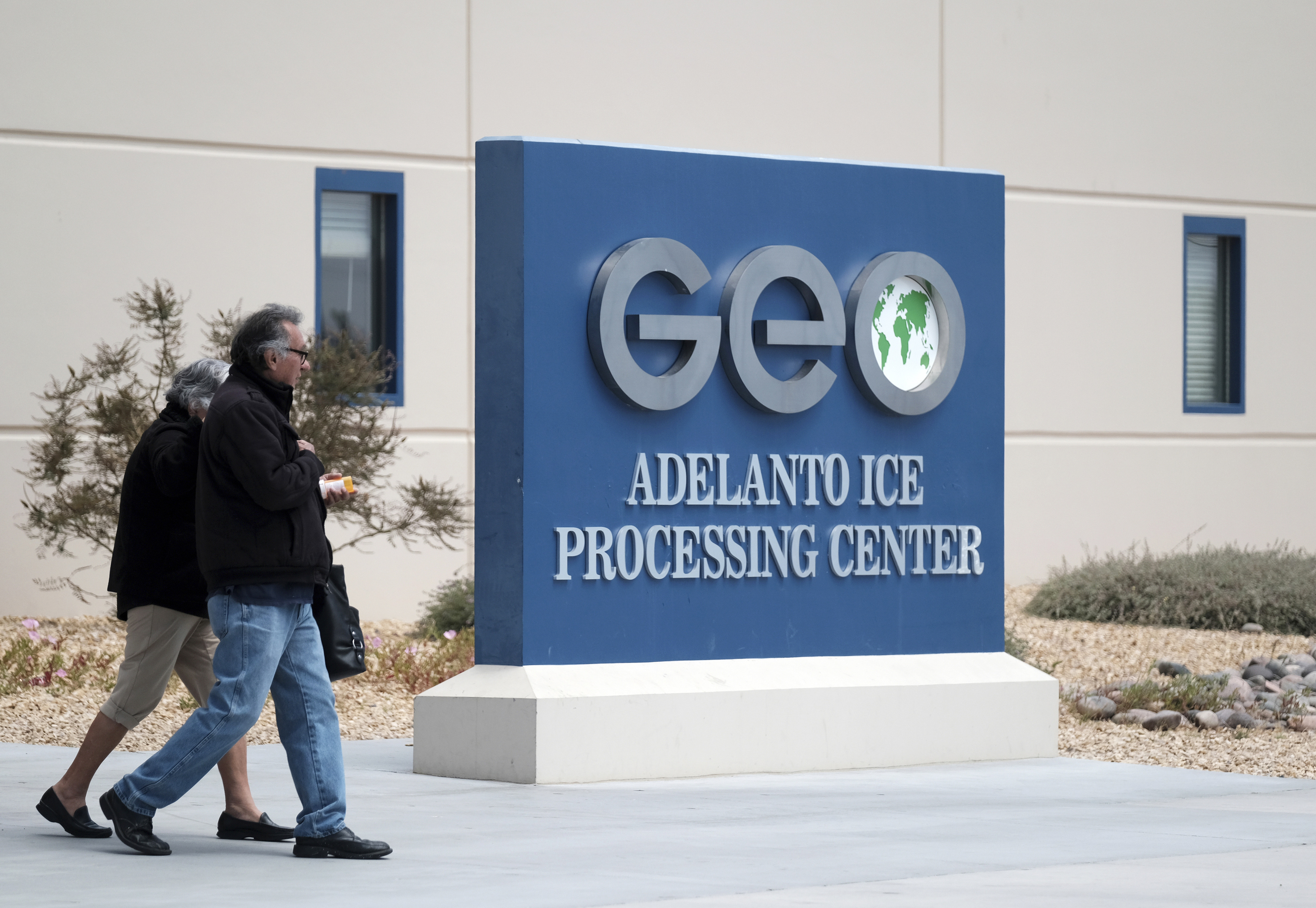 People walk outside the U.S. Immigration and Enforcement Processing Center, operated by GEO Group, Inc. (GEO) a Florida-based company specializing in privatized corrections, on April 20, 2019, in Adelanto, Calif. A larger panel of the 9th U.S. Circuit Court of Appeals on Monday, Sept. 26, 2022, again blocked California's first-in-the-nation ban on for-profit private prisons and immigration detention facilities, finding that it is trumped by the federal government.