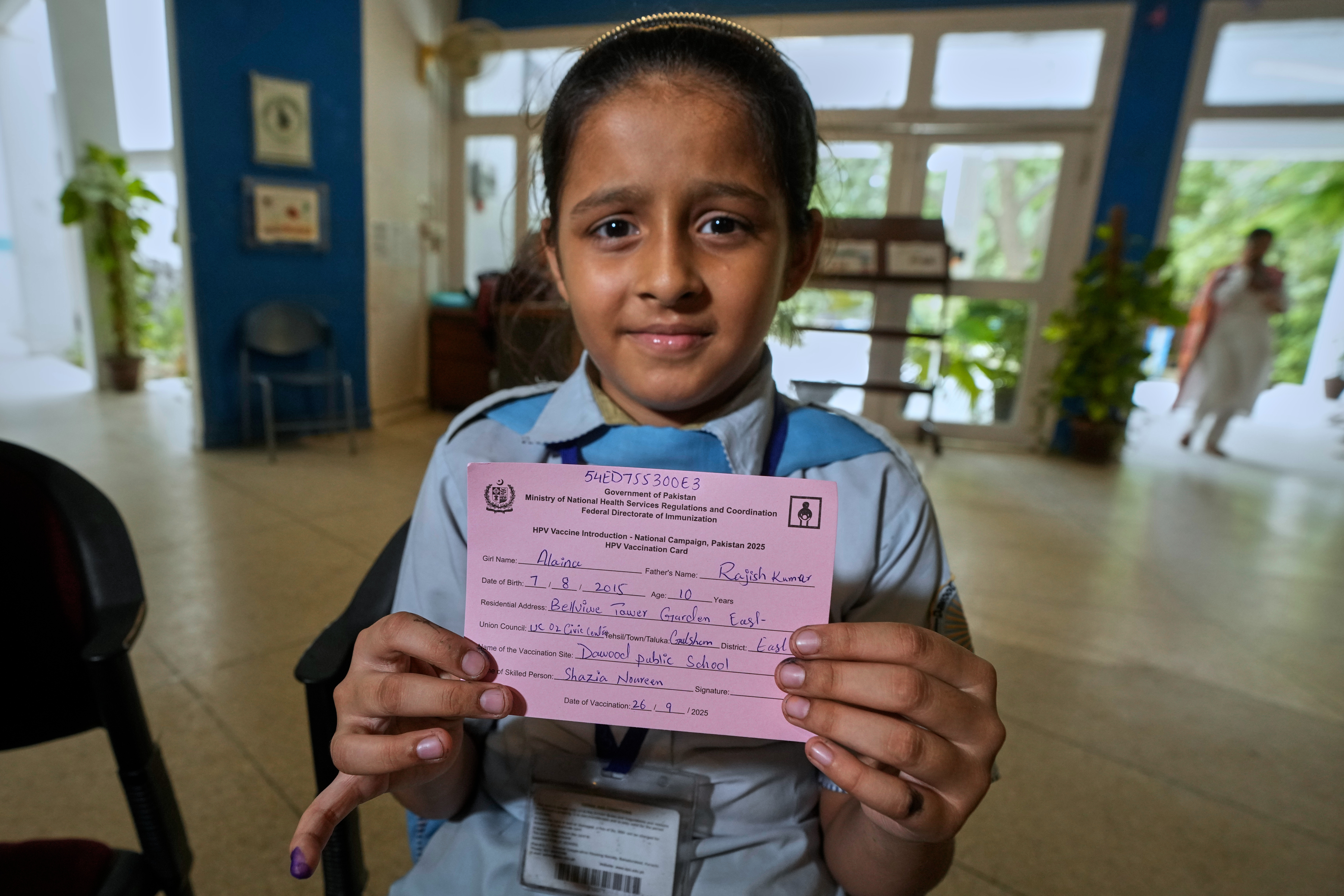 A girl displays a certificate after getting an injection of human papillomavirus (HPV) vaccine from a health worker during a campaign aiming to protect girls from cervical cancer, at a vaccination centre in Karachi, Pakistan, on Friday, September 26, 2025