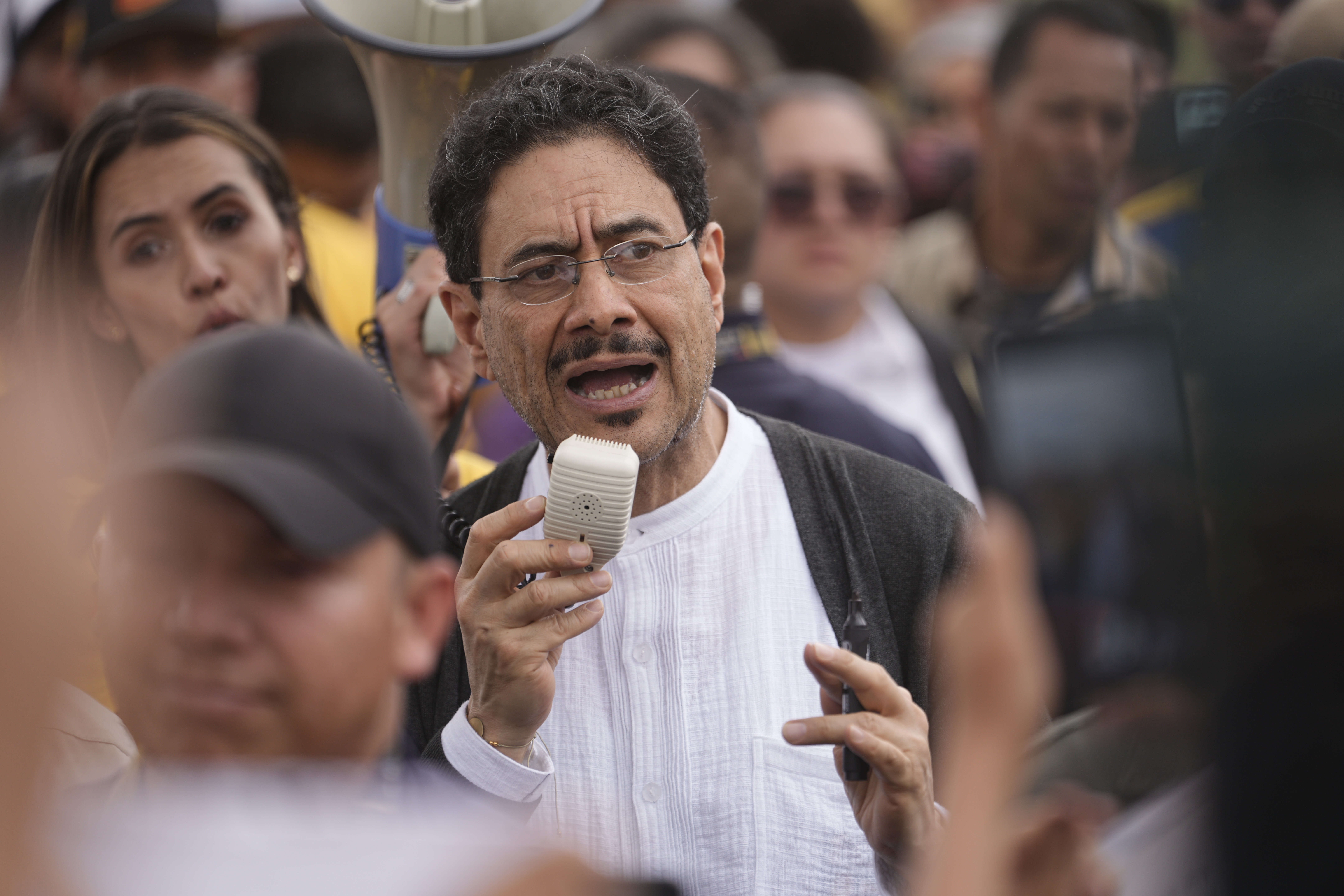Ivan Cepeda speaks into a megaphone while standing in a crowd