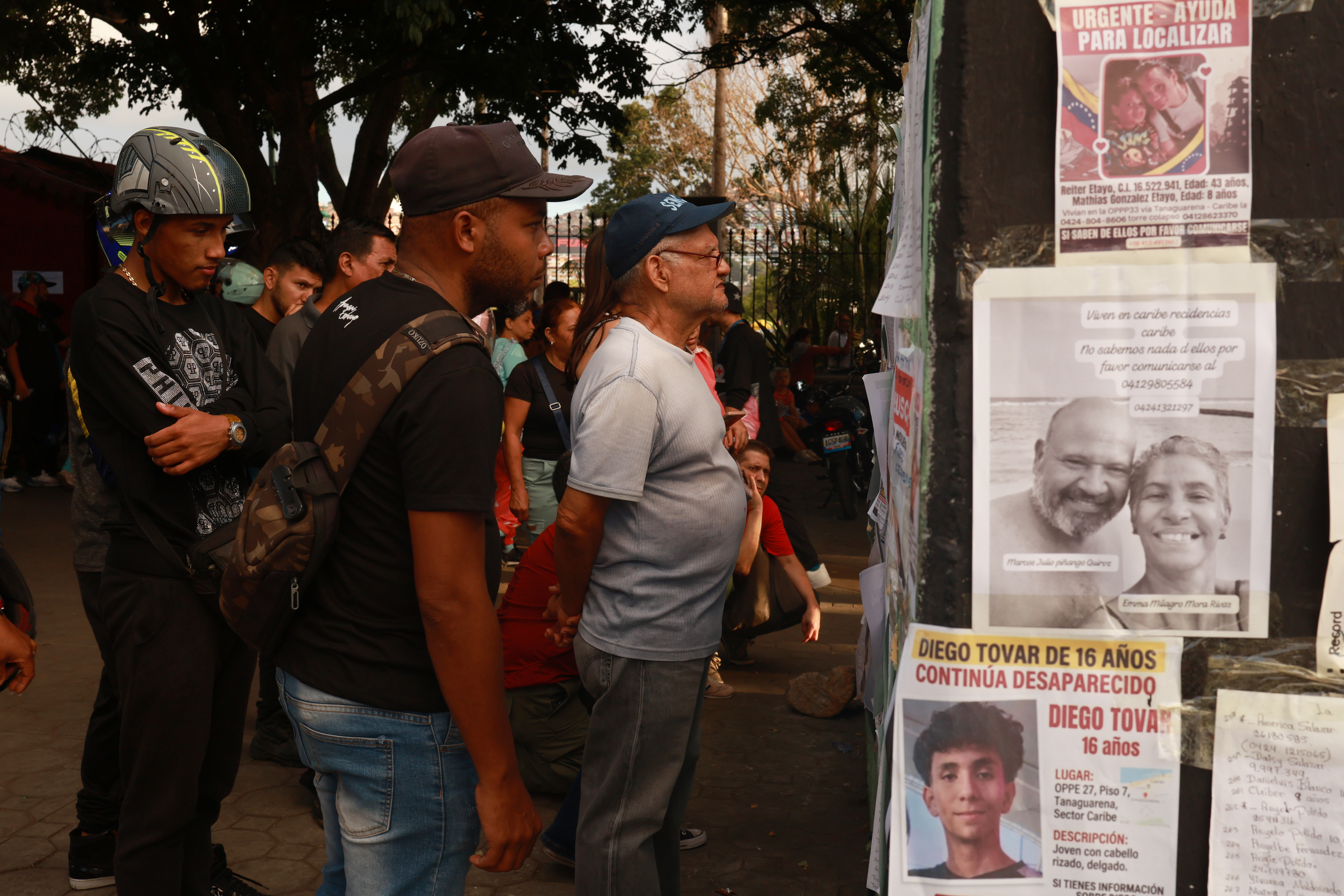 People searching for missing persons check lists three days after twin earthquakes struck La Guaira, Venezuela, Saturday, June 27, 2026. (AP Photo/Javier Campos)