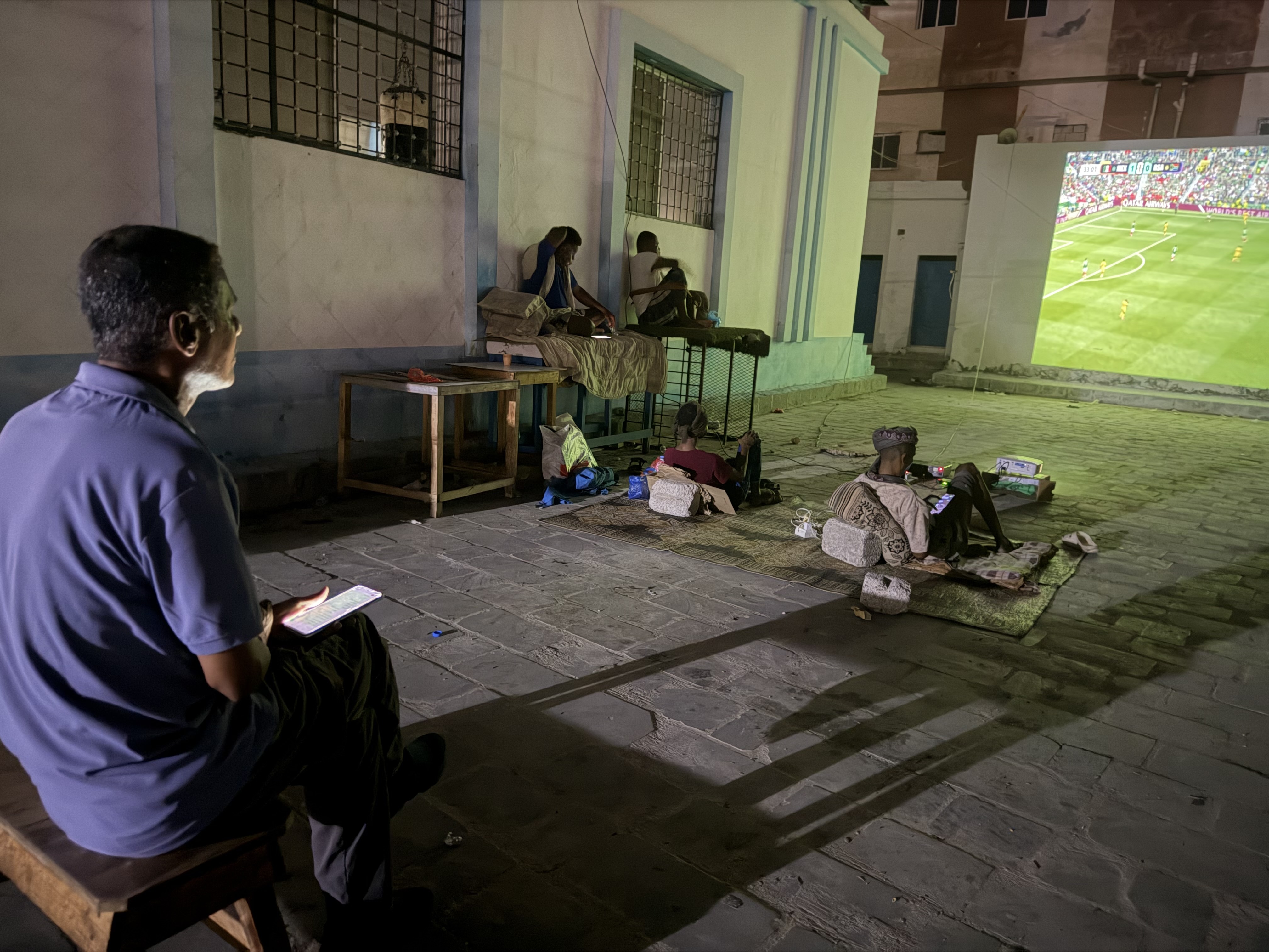 Adel Mohsen watches the opening match of the World Cup on a giant public screen in Mukalla while taking notes for a later football analysis. [Saeed Al-BatatiAl Jazeera]