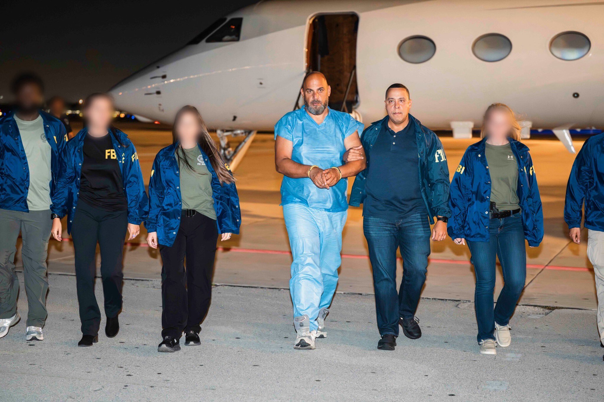 Ibrahim Halimi arrived back in the United States in last Friday aboard a private plane, photographed in light blue detention clothing, hands shackled, flanked by FBI agents. [X@FBIDirectorKash]