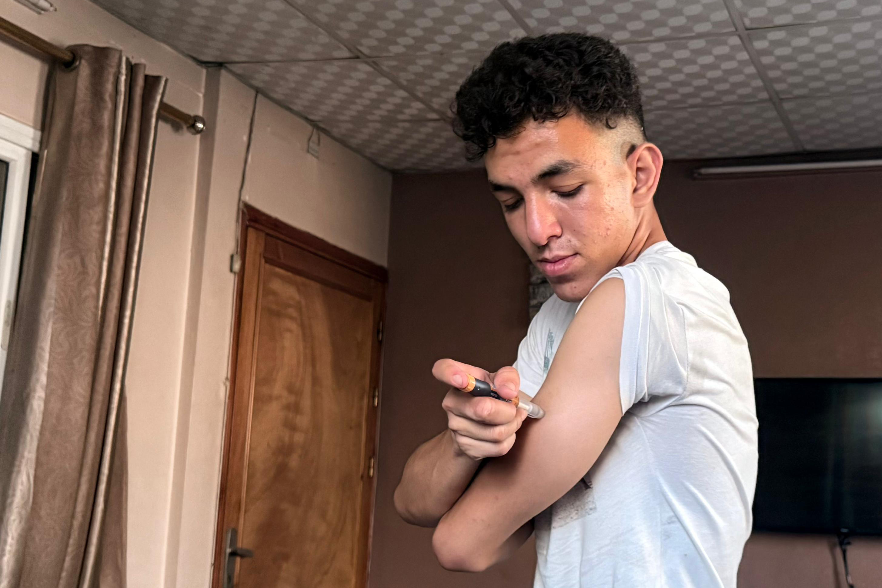 A young man injects himself with insulin.
