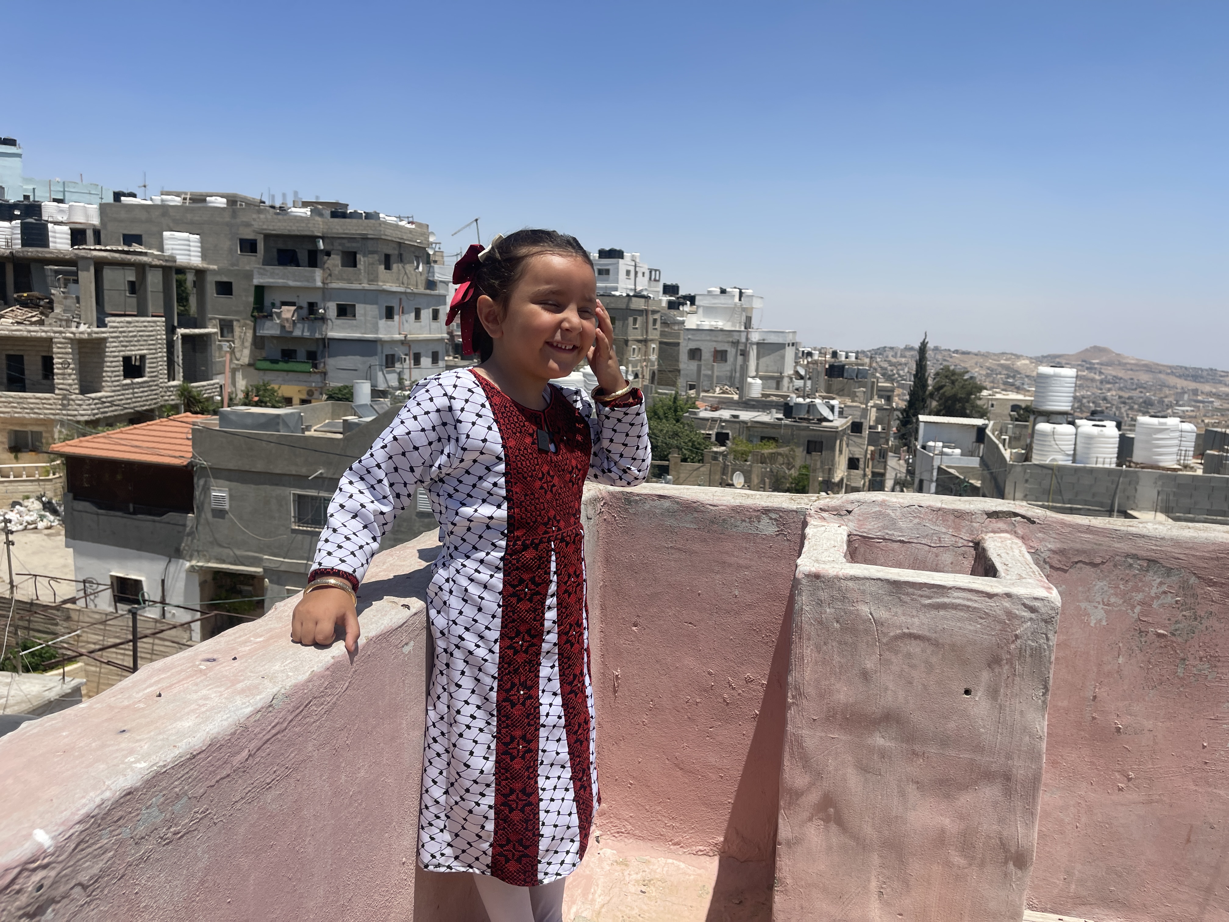 Khour Hammad, 5, stands on a rooftop overlooking Dheisheh refugee camp in Bethlehem, in the occupied West Bank. Both of her parents have been arrested by Israeli forces [Leila Warah/Al Jazeera].